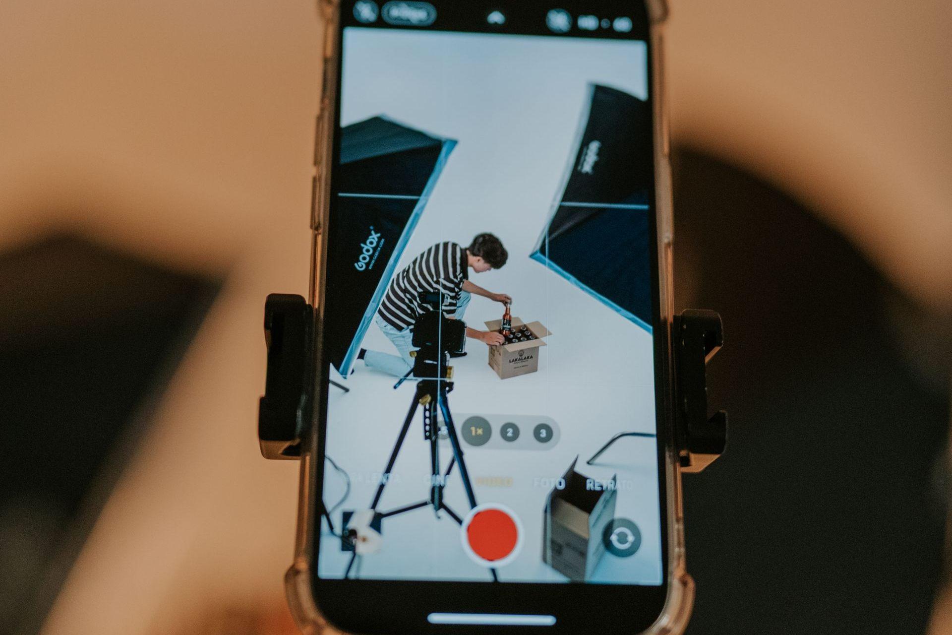 Phone mounted on a tripod filming a product shoot on a white cyclorama
