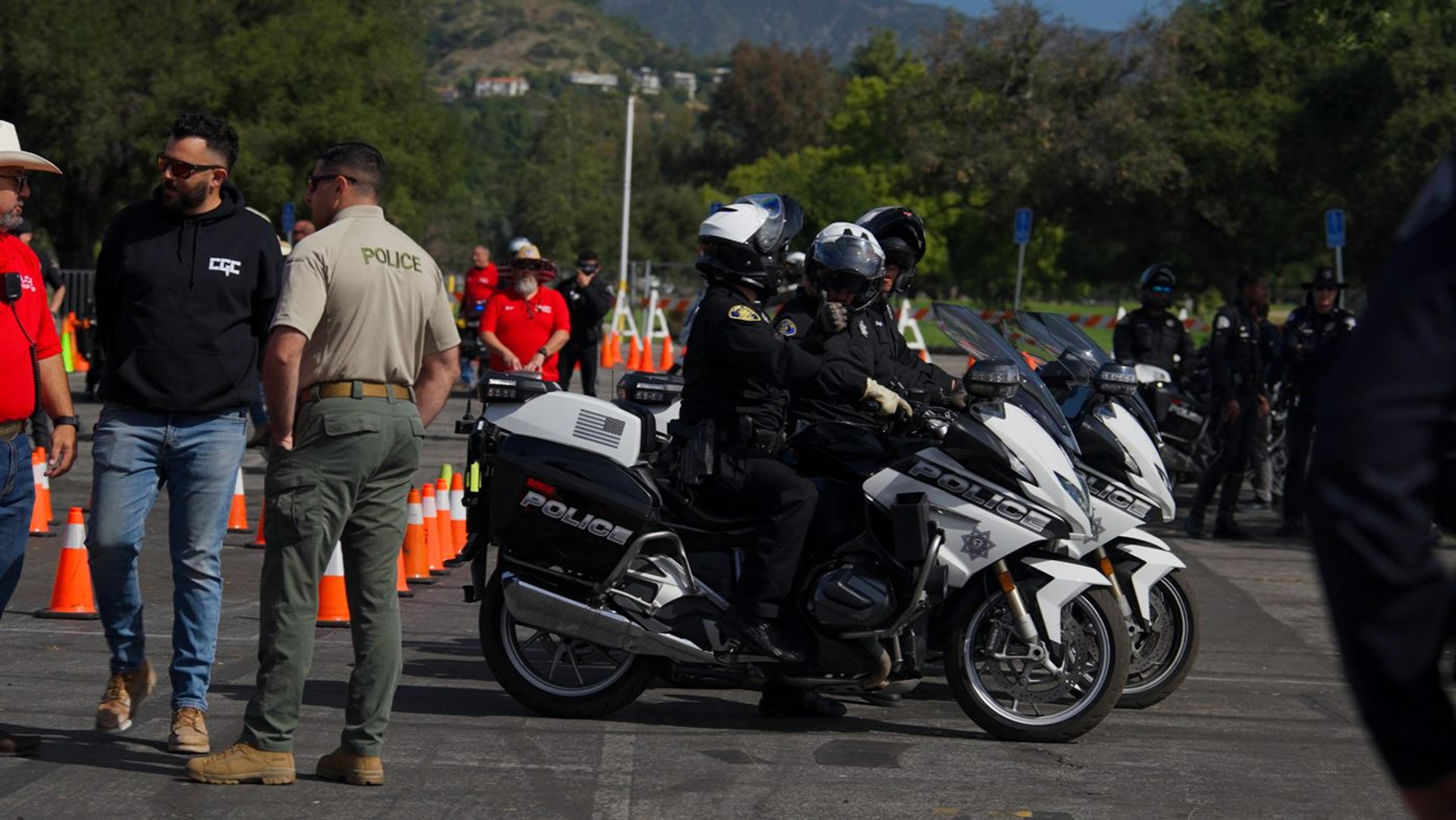 Police motorcycle escort staged with crew and marshals at the start of an event route