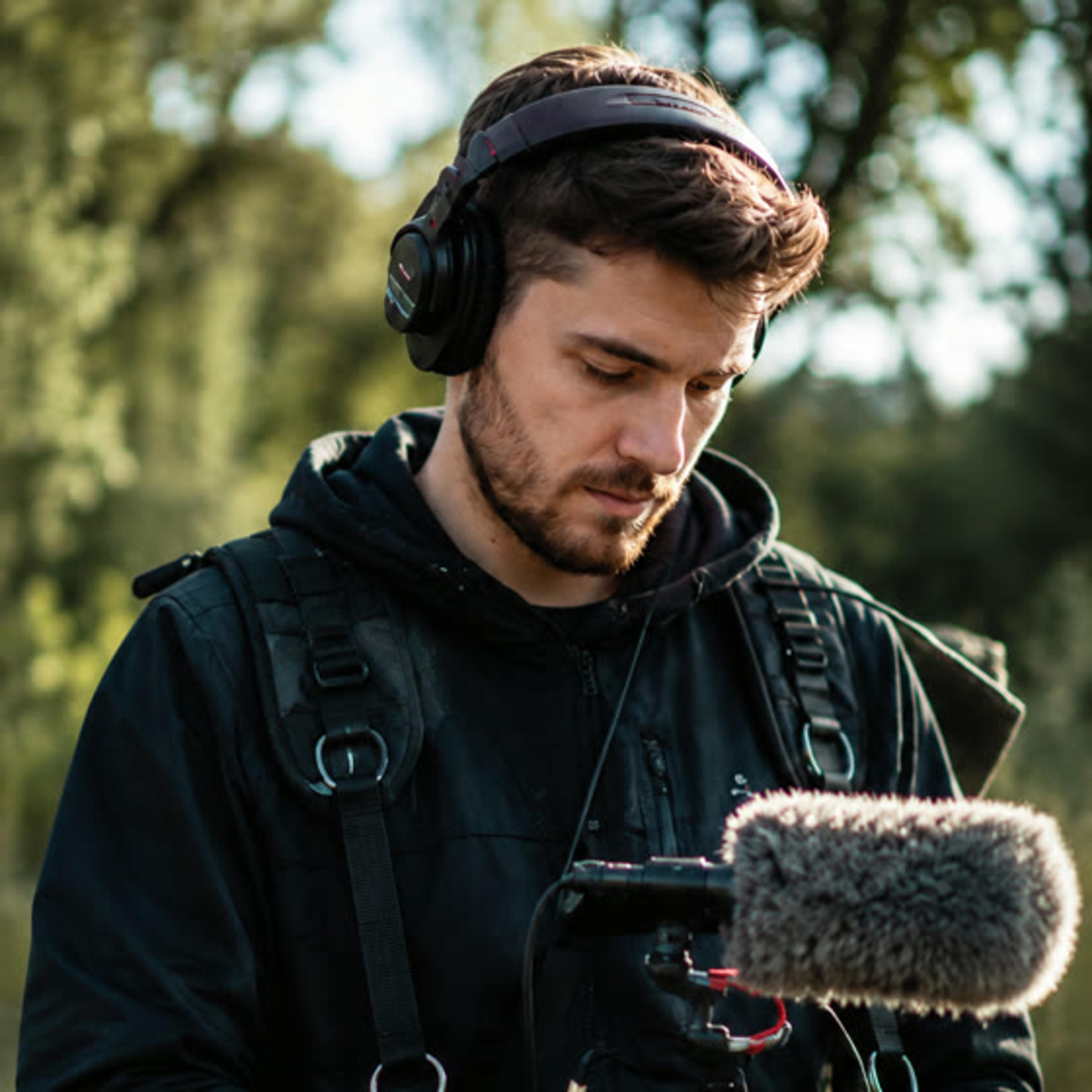 Production sound mixer with headphones and a boom microphone