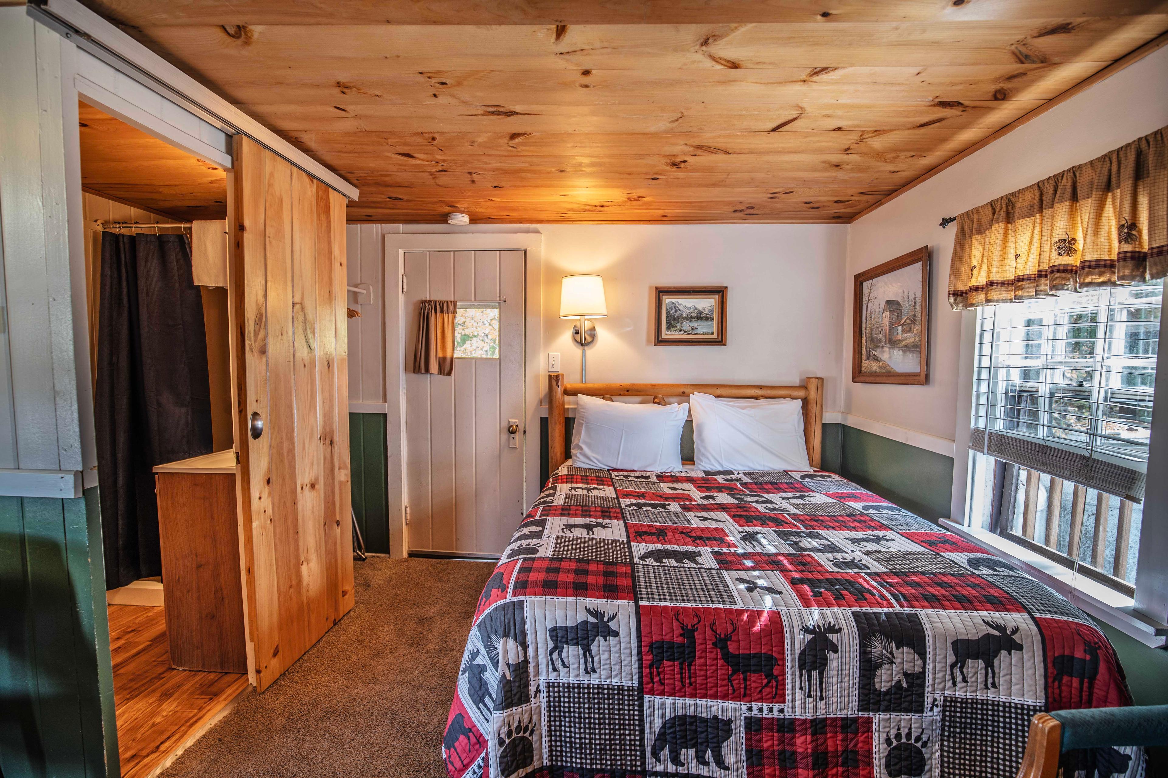 Bedroom with plush queen-sized bed at The Basin cabin. #NatureLovers #CabinGetaway #ScenicViews #YearRoundComfort