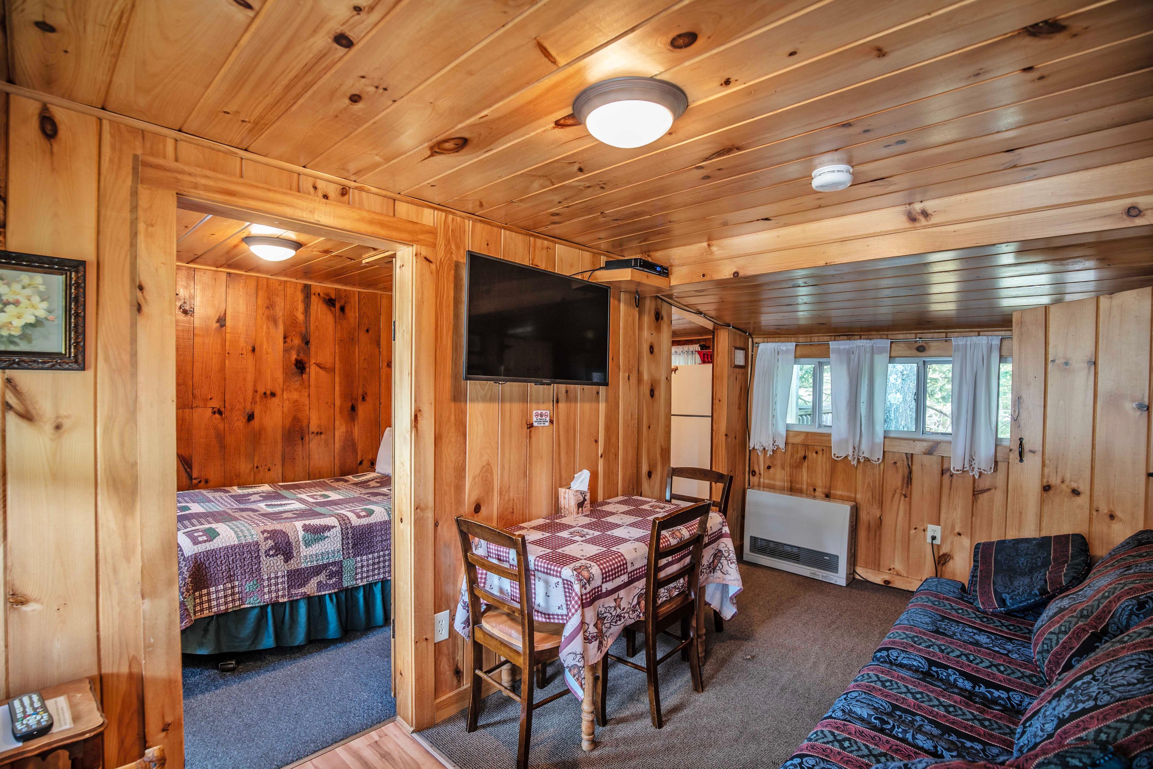 Cozy living room with TV and dining area at Eagle Cliff cabin. #RusticCharm #FamilyVacation #GroupAccommodation #CabinWithAView