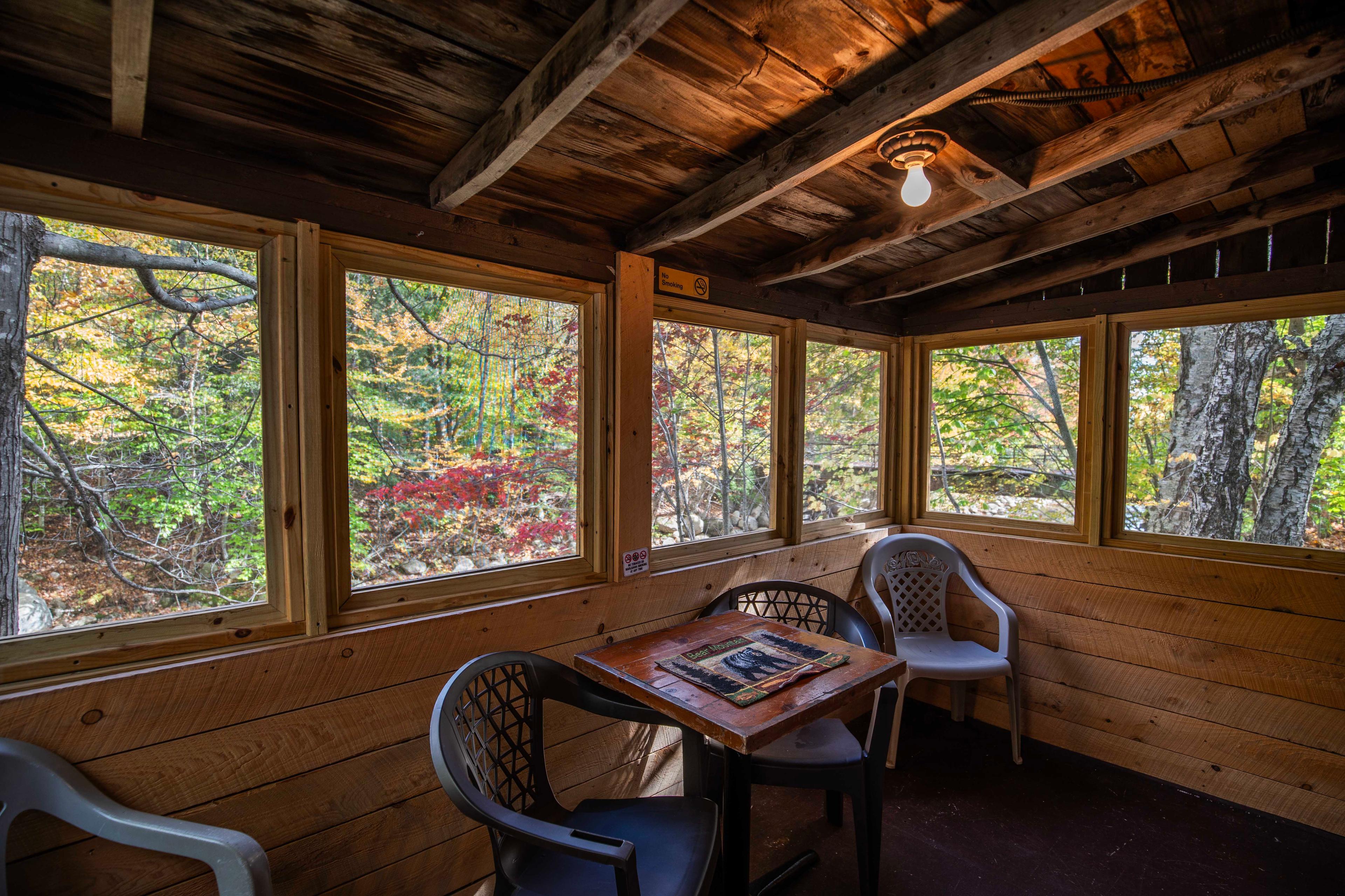 Outdoor dining space on the screened-in porch of The Bears Den cabin. #YearRoundComfort #VacationRental #MountainRetreat