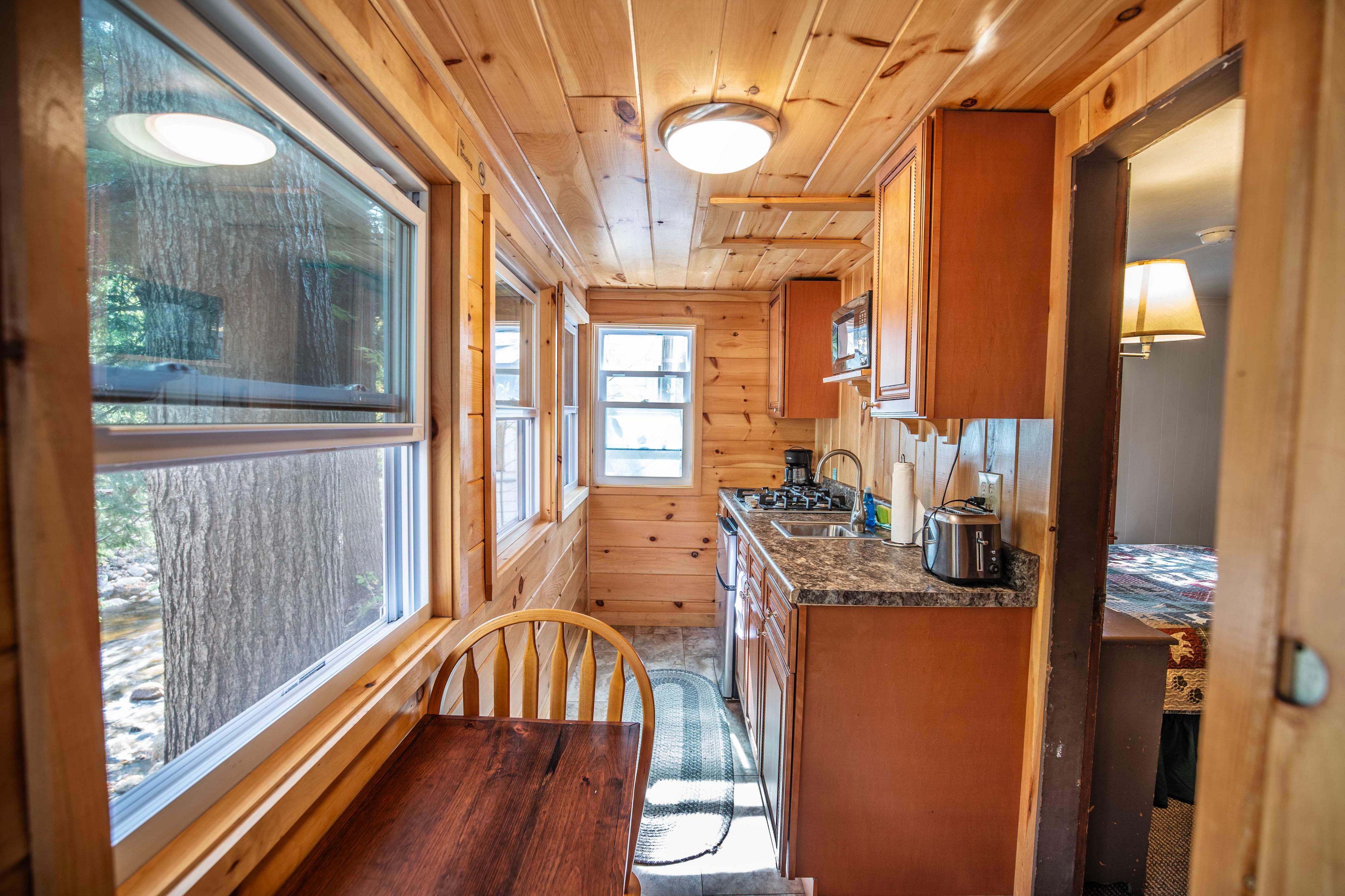 Serene riverfront views from the kitchen in Falling Waters cabin. #ScenicViews #YearRoundComfort #VacationRental #MountainRetreat