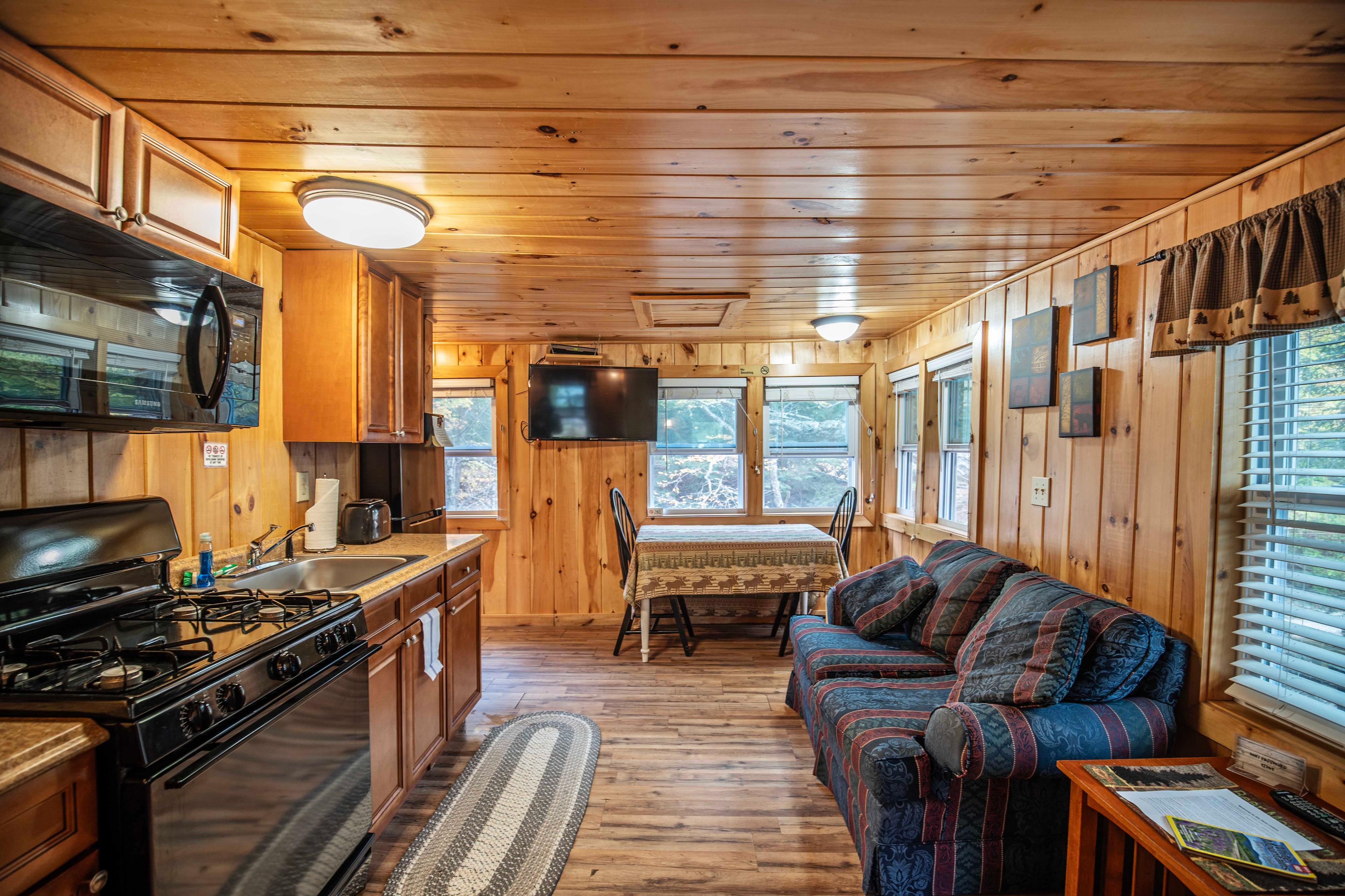 Comfortable couch and TV in the living area of Fox Hollow cabin. #LincolnNH #WhiteMountains #CabinRetreat #NatureEscape