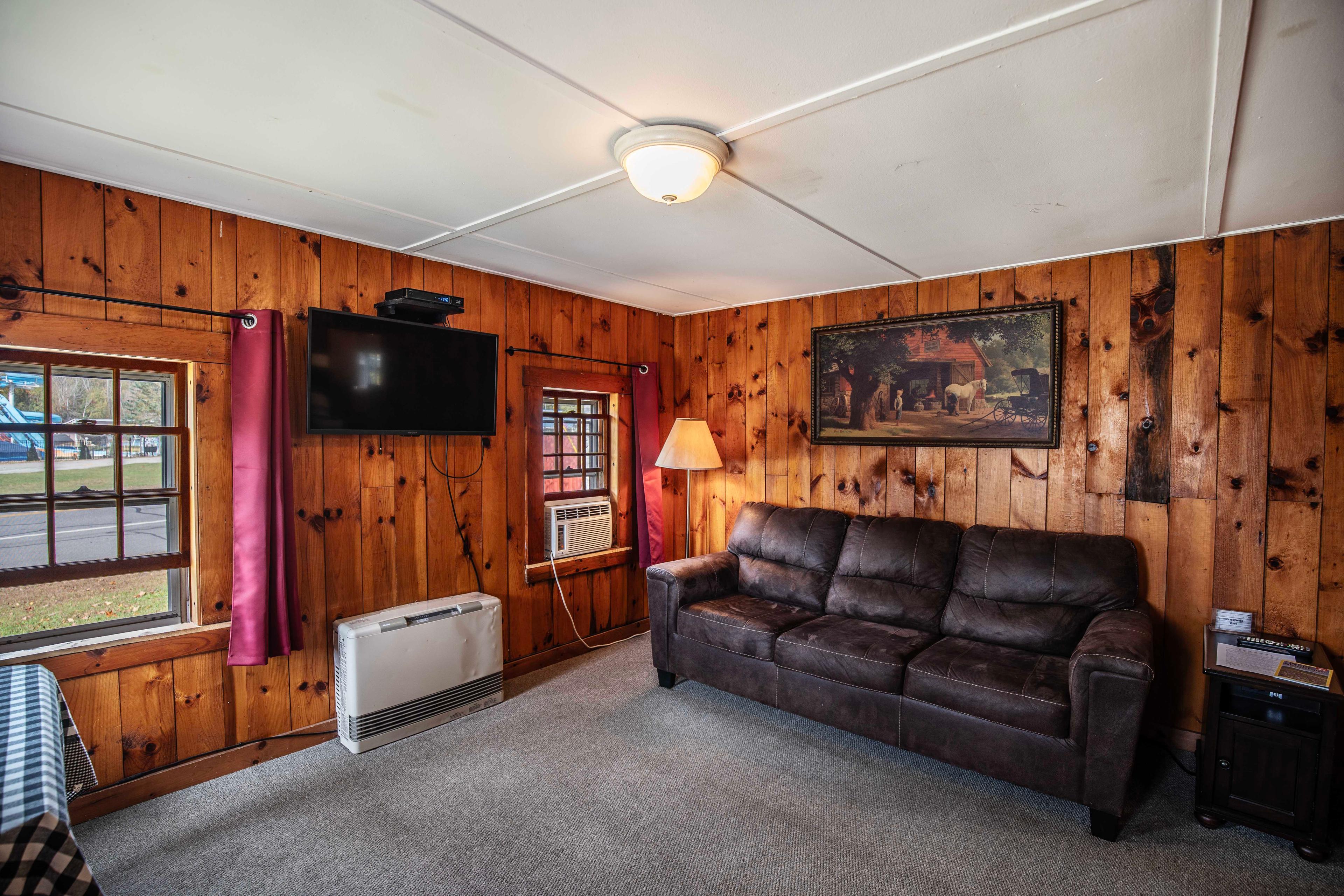 Comfortable couch and TV setup in the living room of The Pemi Trail. #CabinGetaway #RusticCharm #CozyCabin #NatureRetreat