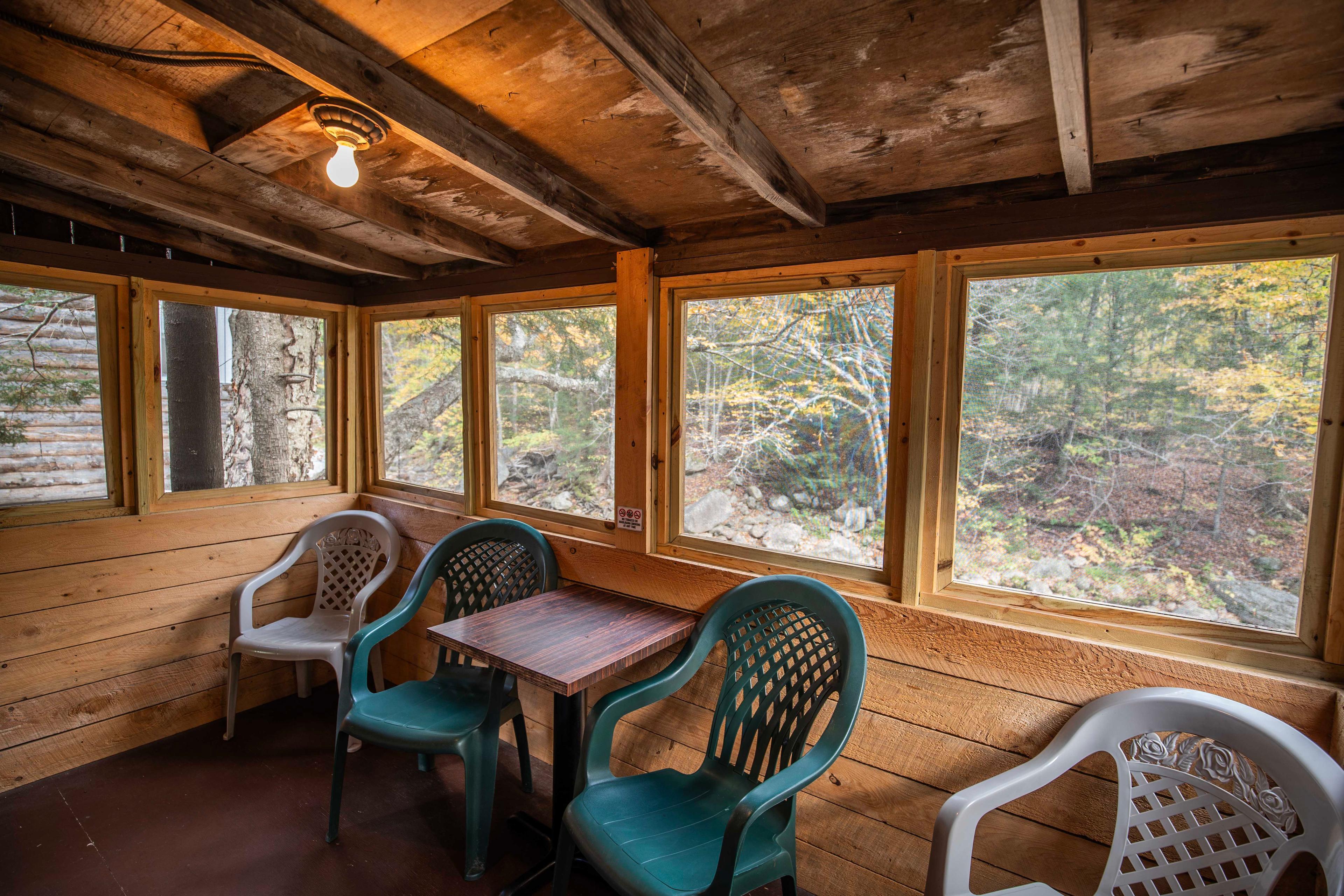 Relax and unwind on the screened-in porch of The Moose's Antler cabin. #FirewoodAvailable #MountainViews #TravelNH #RiverstoneFireplace