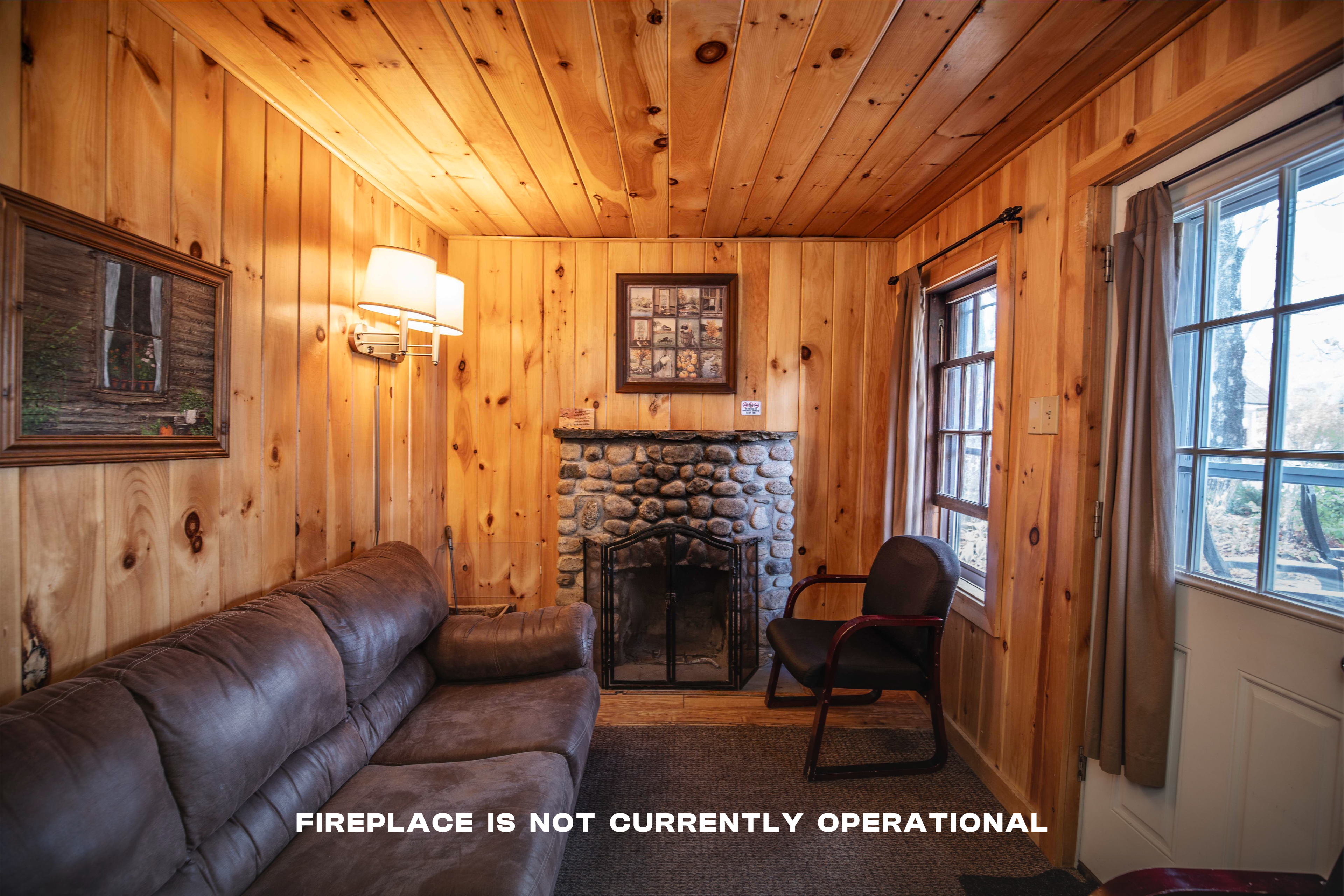 Welcoming living room with riverstone fireplace in The Moose's Antler cabin. #OutdoorDining #FamilyFun #FirepitNights