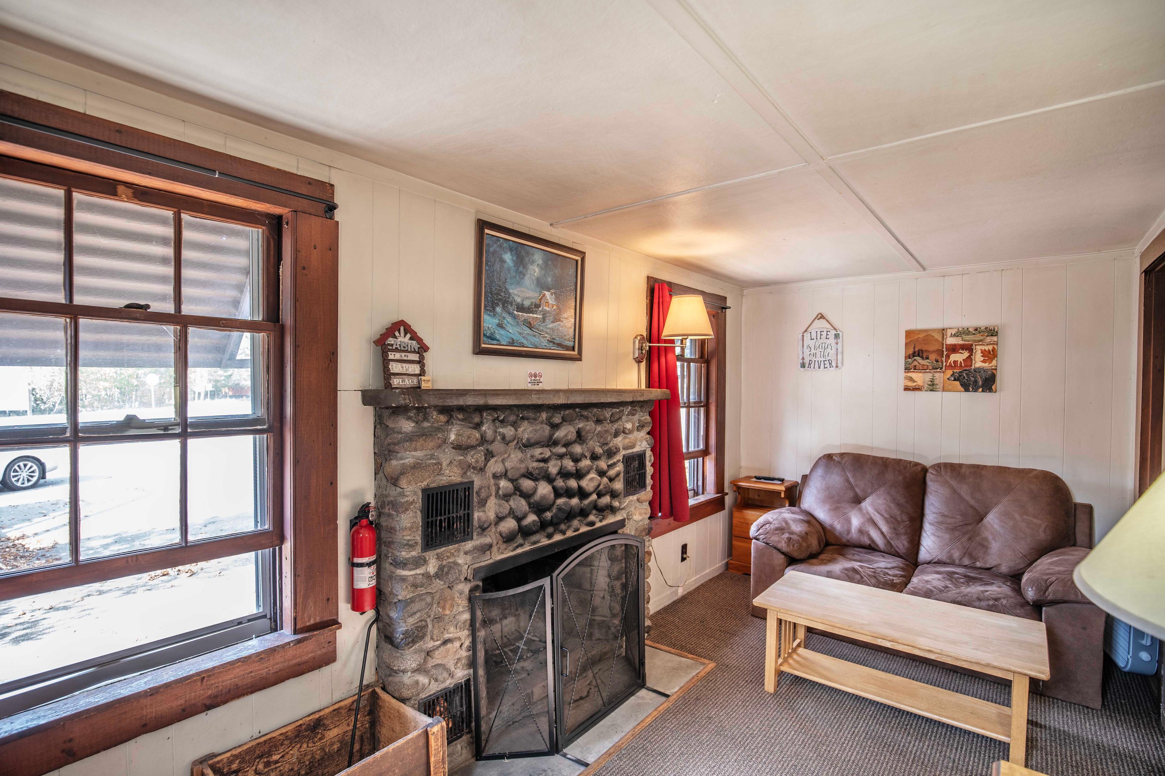 Welcoming living room with riverstone fireplace and comfortable seating at Falling Waters. #MorningCoffee #EveningRelaxation #ScreenedInPorch #CozyLivingRoom