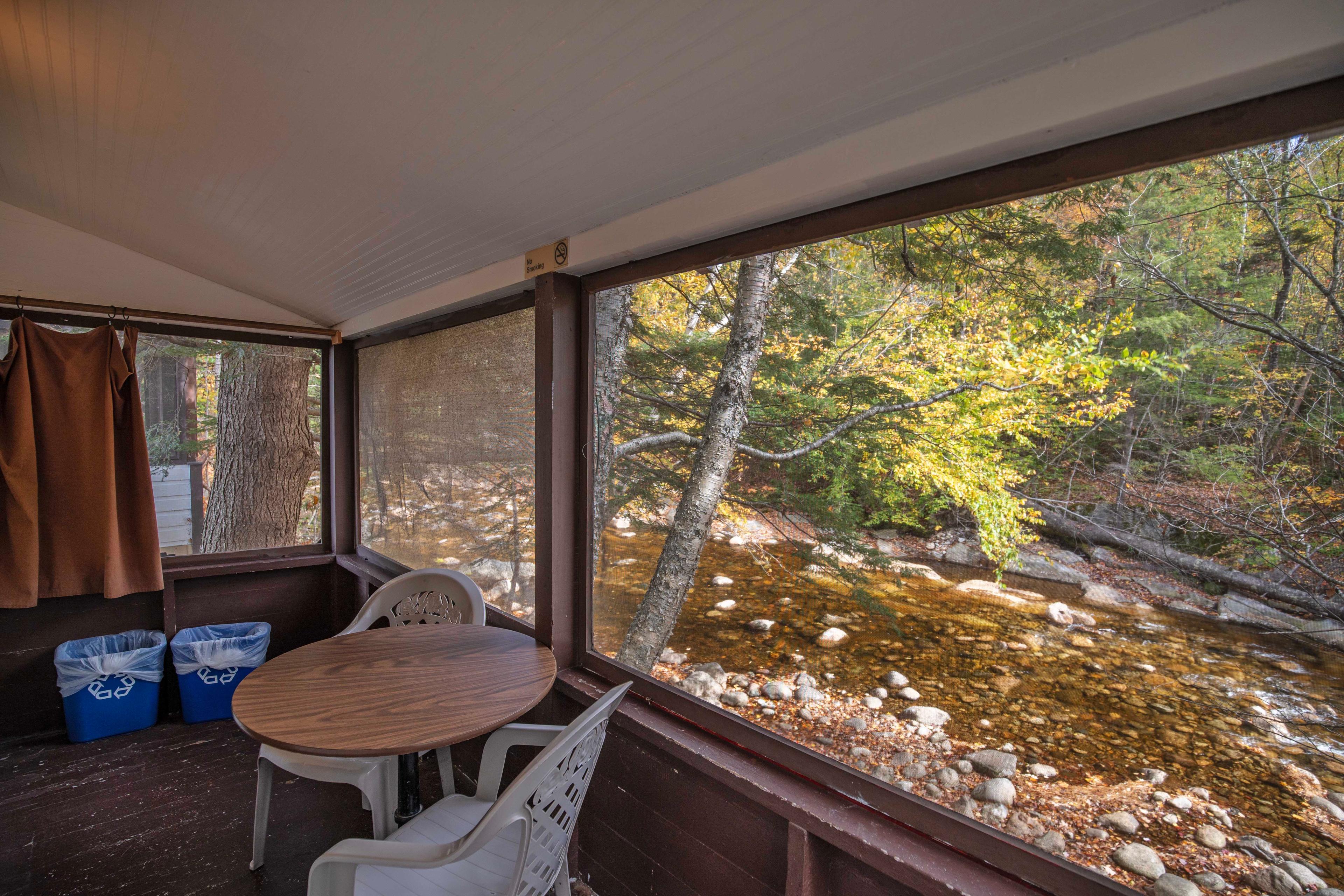 Relax and unwind on the screened-in porch of The Flume cabin, overlooking the Pemigewasset River. #RomanticGetaway #UnforgettableGetaway #CabinInTheWoods #RelaxationSpot