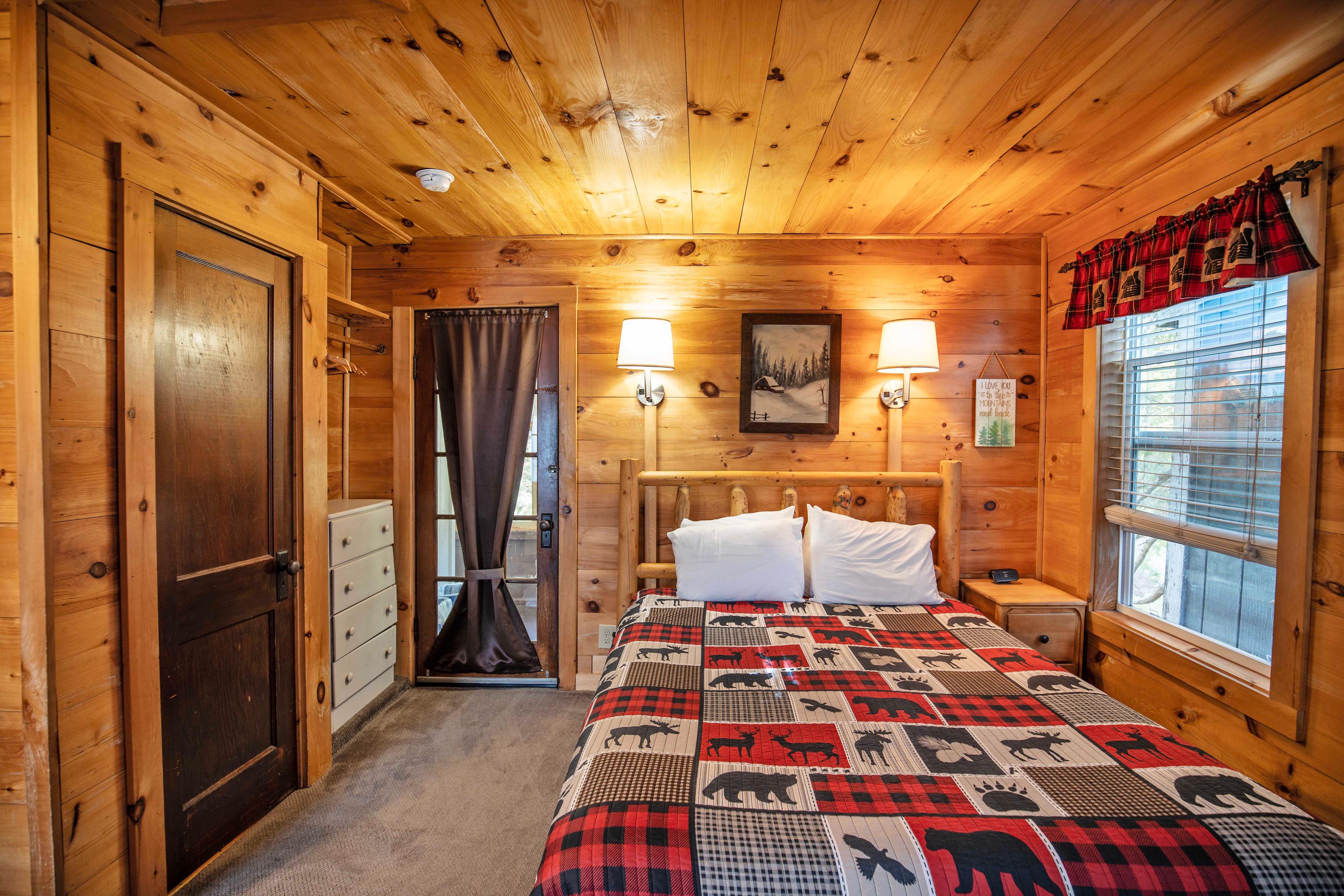 Bedroom with a plush queen-sized bed in Beaver Pond cabin. #RusticMeetsModern #RiverViews #PeacefulRetreat #FirewoodAvailable