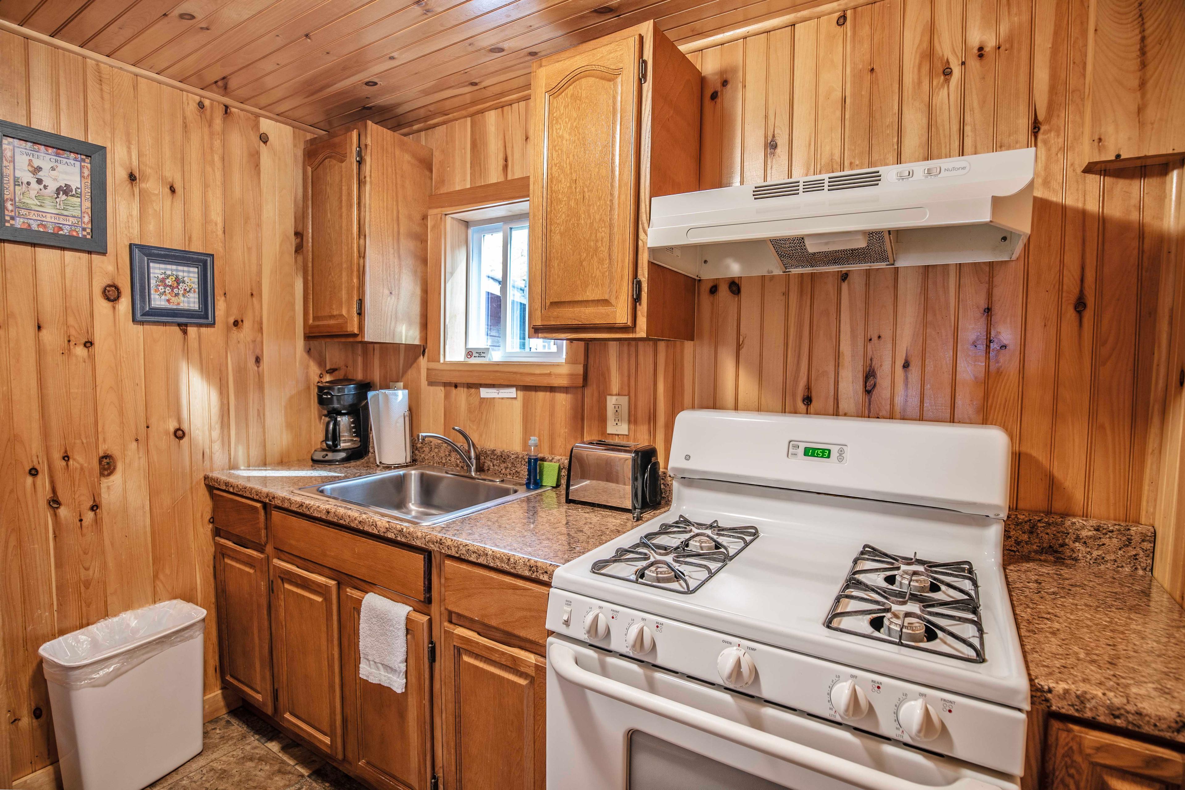 Well-equipped kitchen featuring gas stovetop and full-sized refrigerator. #VacationHome #AirbnbNH #PemiRiver #CabinLiving