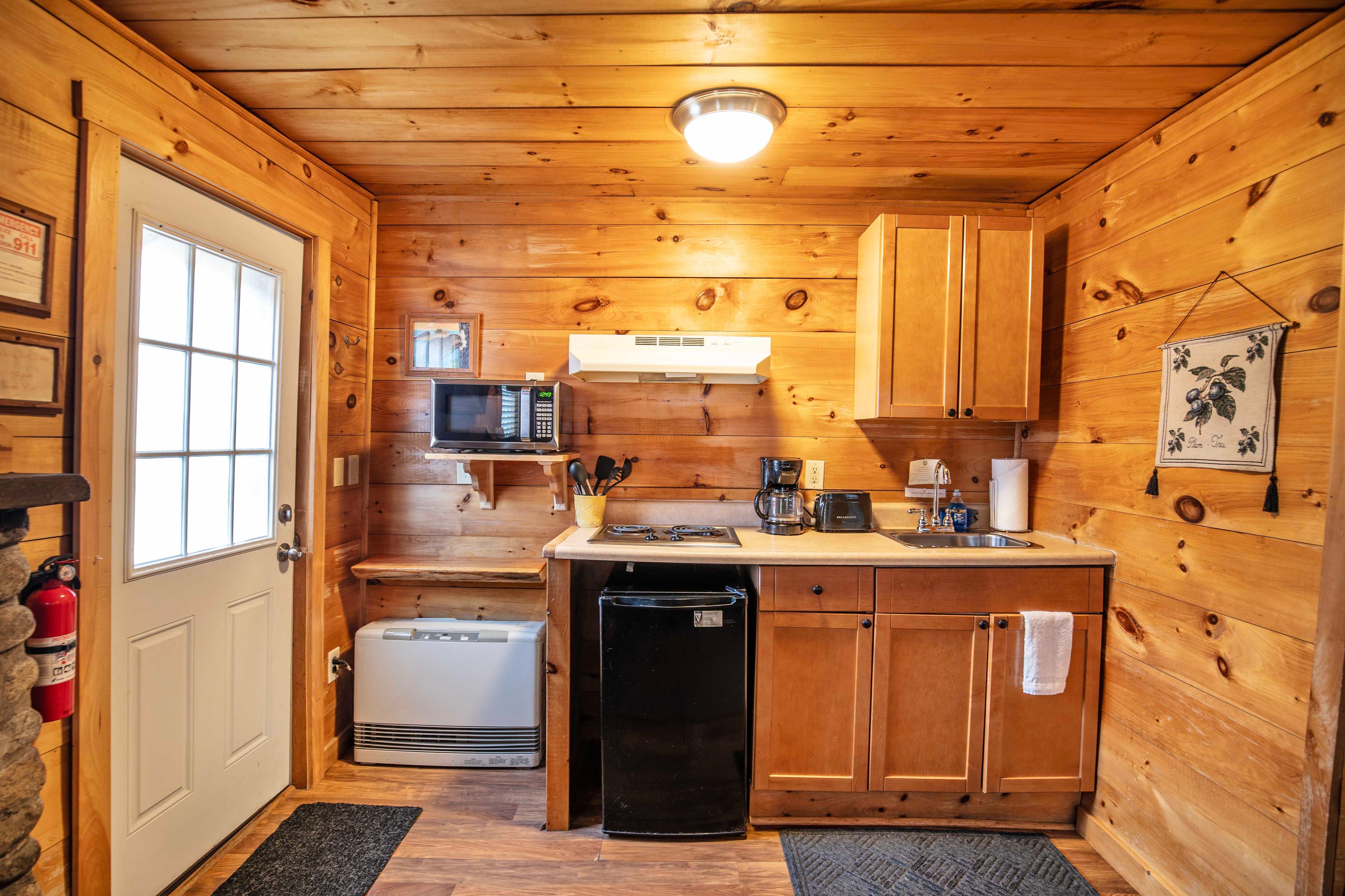 Well-equipped kitchen in Beaver Pond cabin, featuring a mini-fridge, microwave, and stovetop. #CozyCabin #FireplaceNights #RusticCharm #NatureLovers