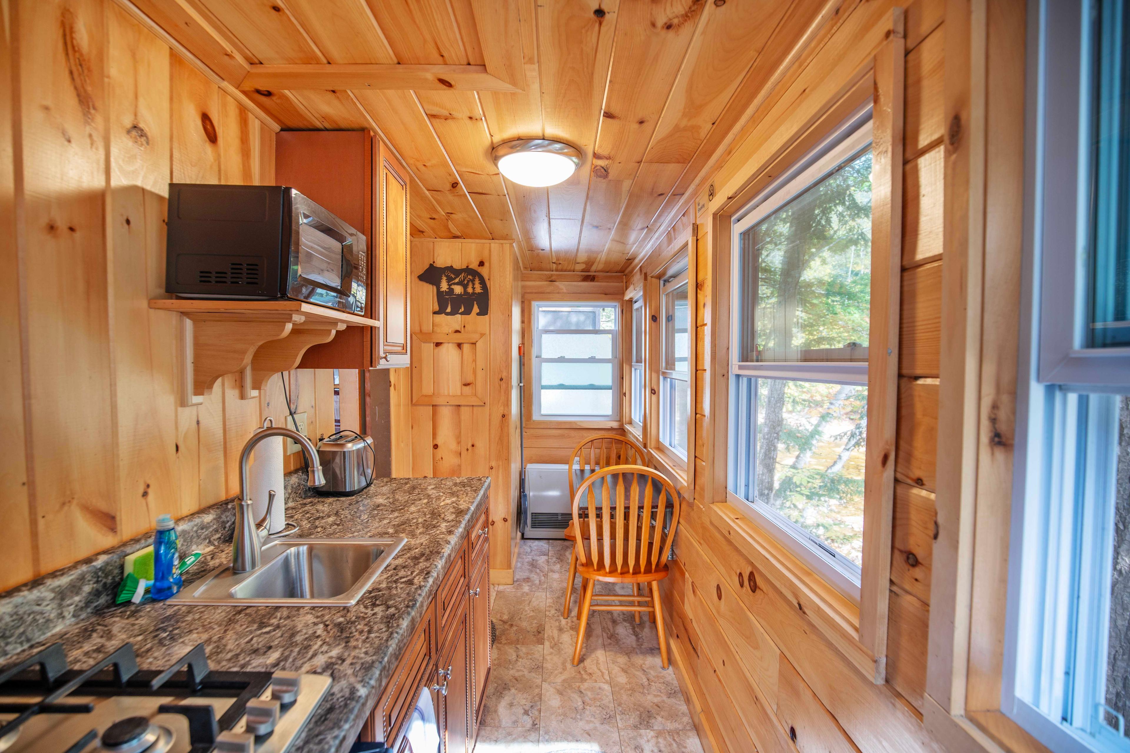 Well-equipped kitchen with mini-fridge, microwave, and stovetop in Falling Waters. #NatureEscape #CozyCabin #FireplaceNights #RusticCharm