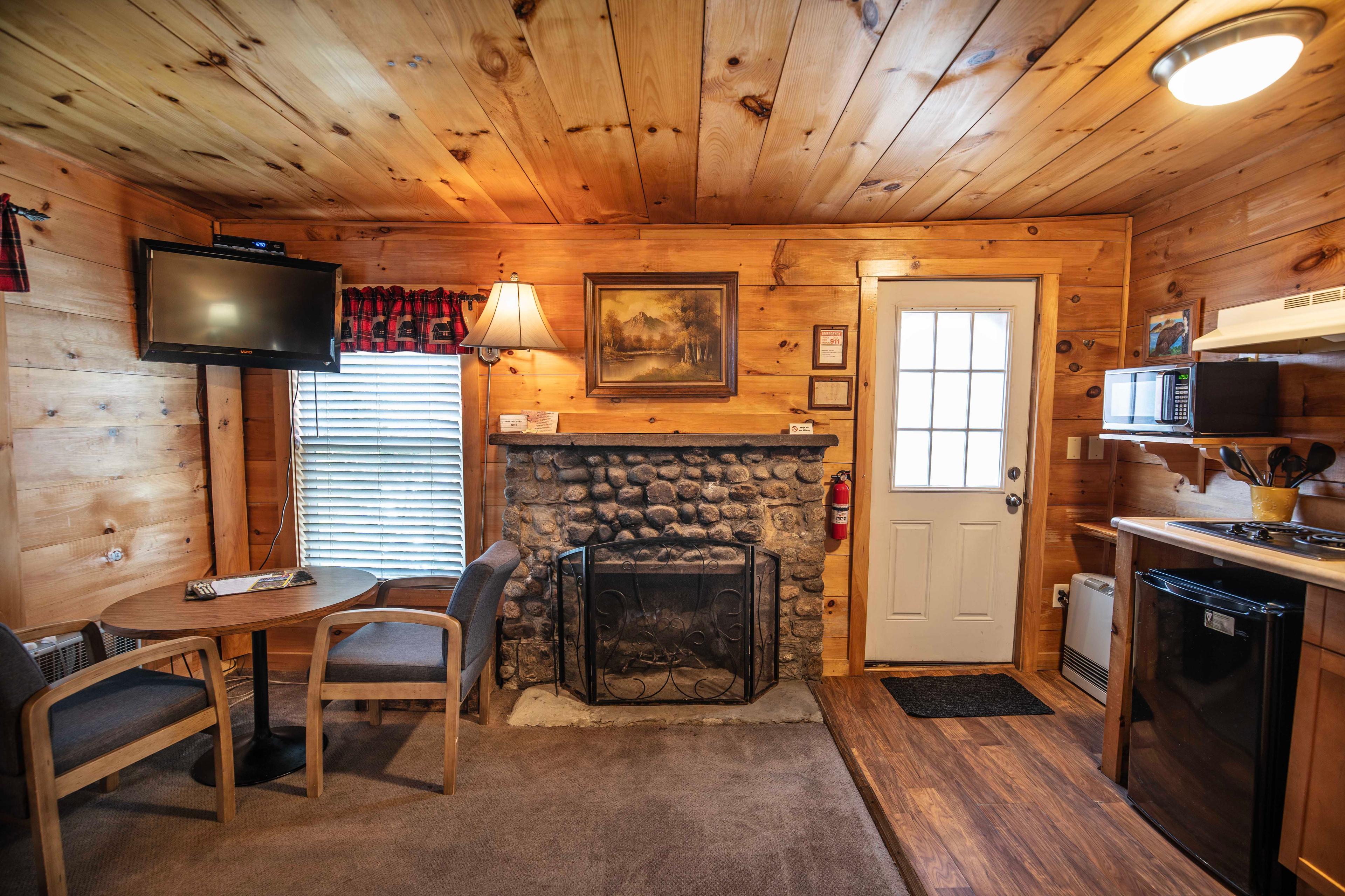 Gather around the beautiful riverstone fireplace in Beaver Pond cabin. #PeacefulRetreat #FirewoodAvailable #RomanticCabin #ScenicPorch