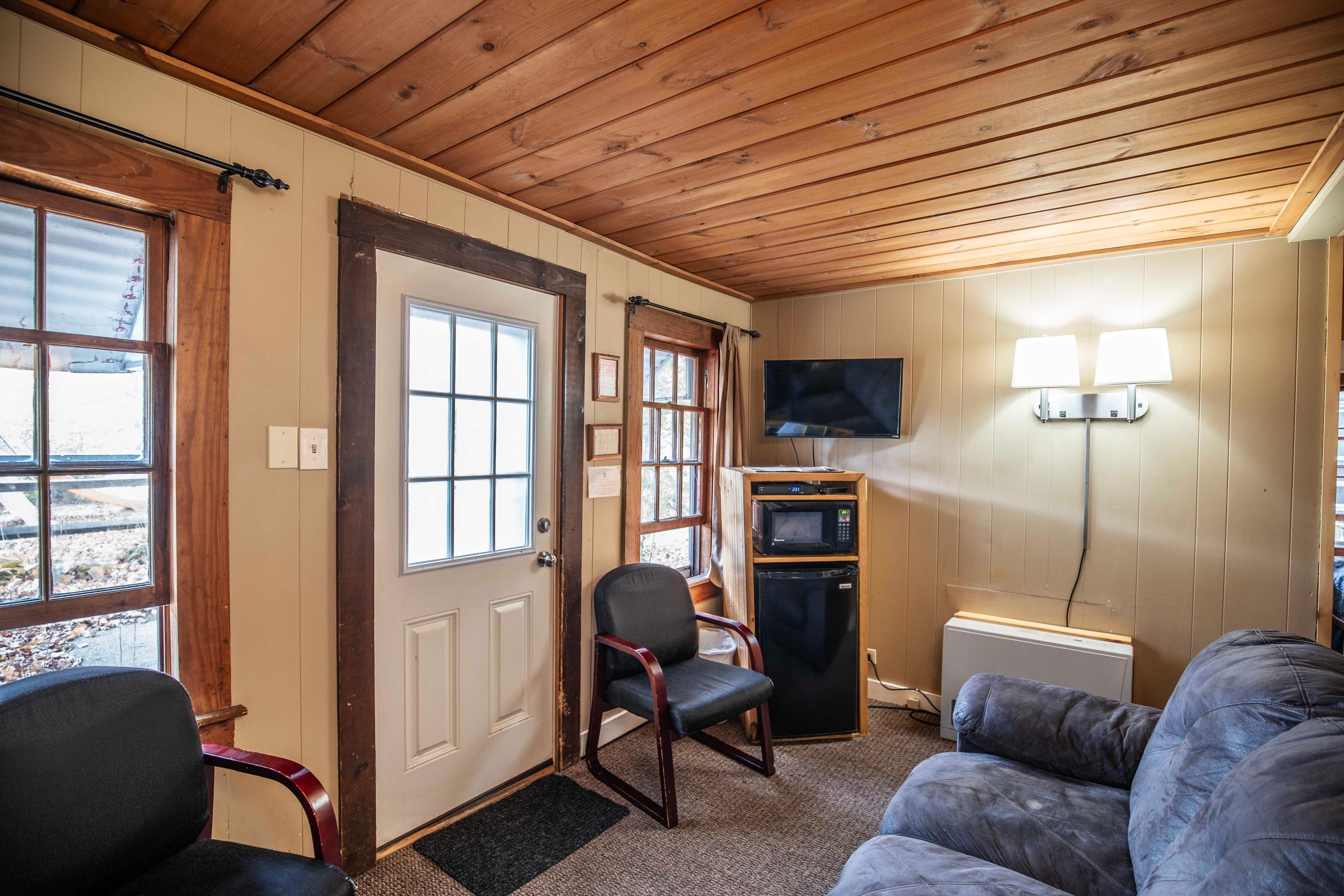 Cozy living room in The Bears Den with a riverstone wood-burning fireplace. #NatureLovers #CabinGetaway #ScenicViews #YearRoundComfort