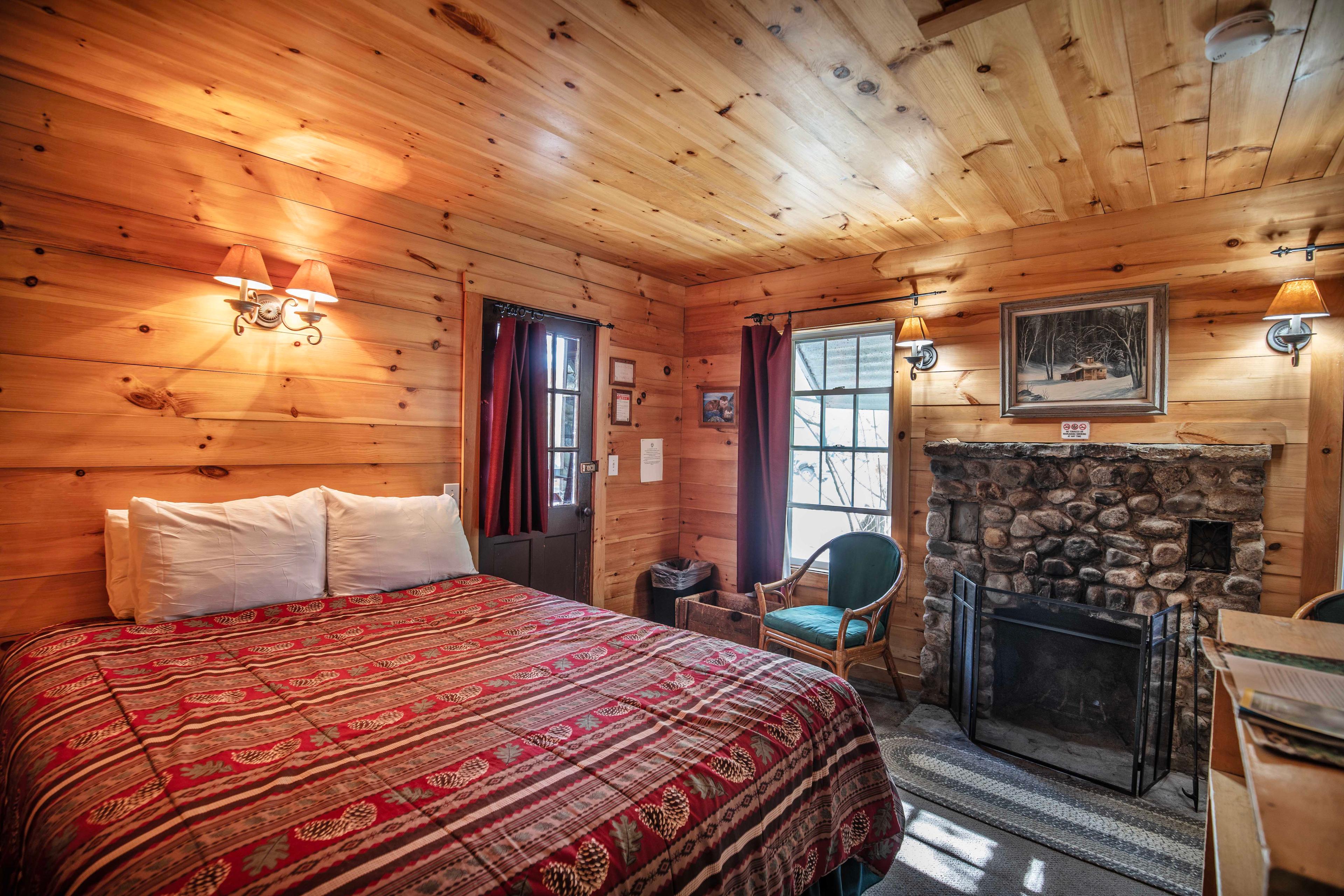 Warm and inviting interior with a riverstone fireplace in The River Otter cabin. #LincolnNH #WhiteMountains #CabinRetreat #NatureEscape