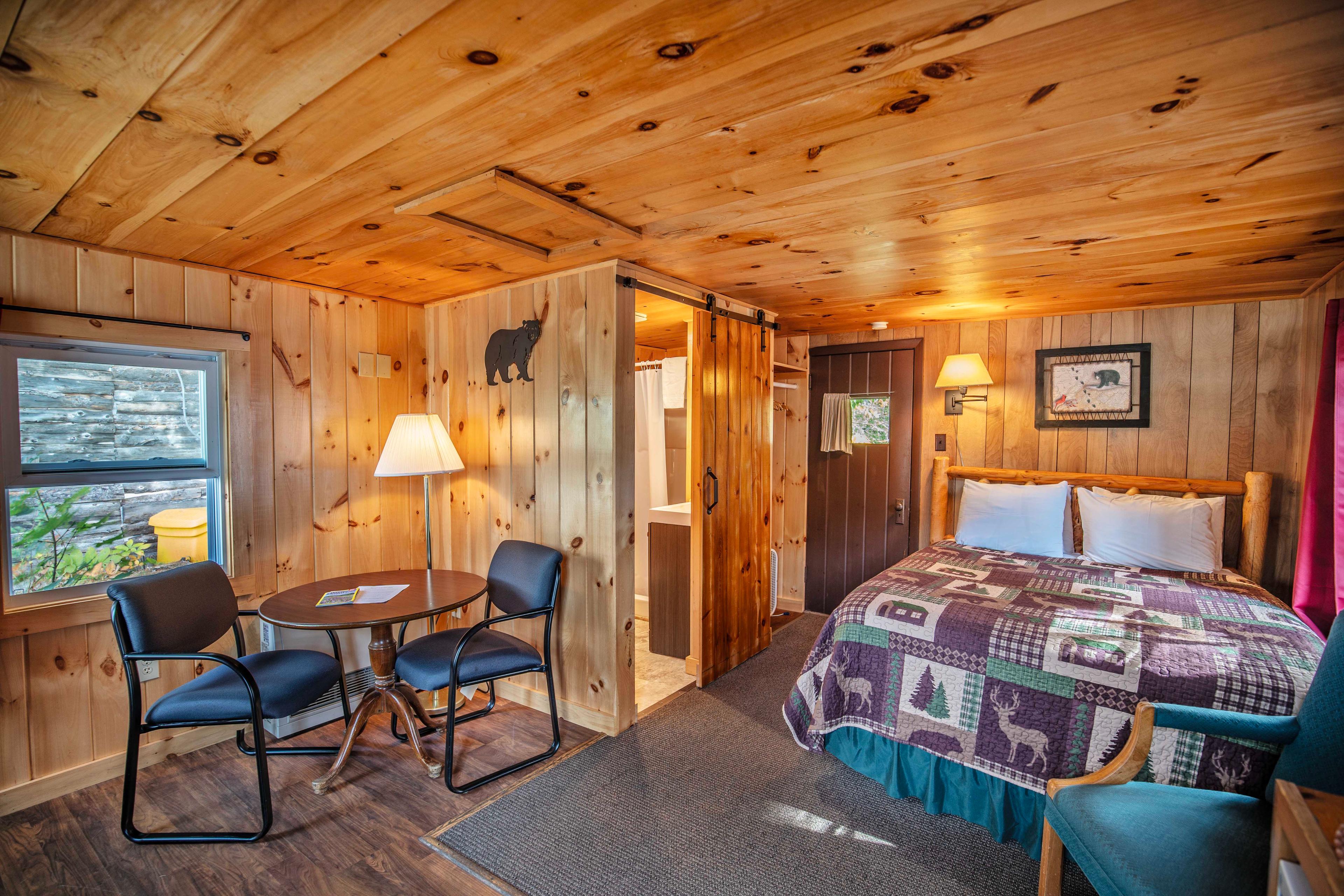 Inviting circular dining table and TV area next to fireplace in Cathedral Ledge cabin. #NatureEscape #RiverfrontViews #CabinLife #OpenLivingSpace