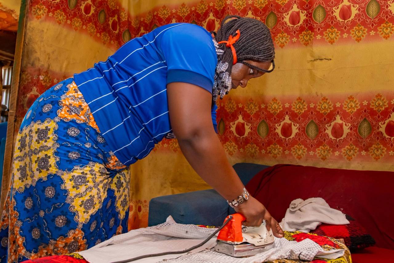 A woman irons clothes with an old iron.