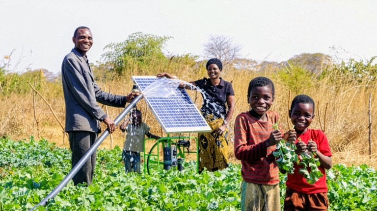 A family waters a field of green crops using a solar-powered irrigation pump, with two smiling children holding leafy greens in the foreground.