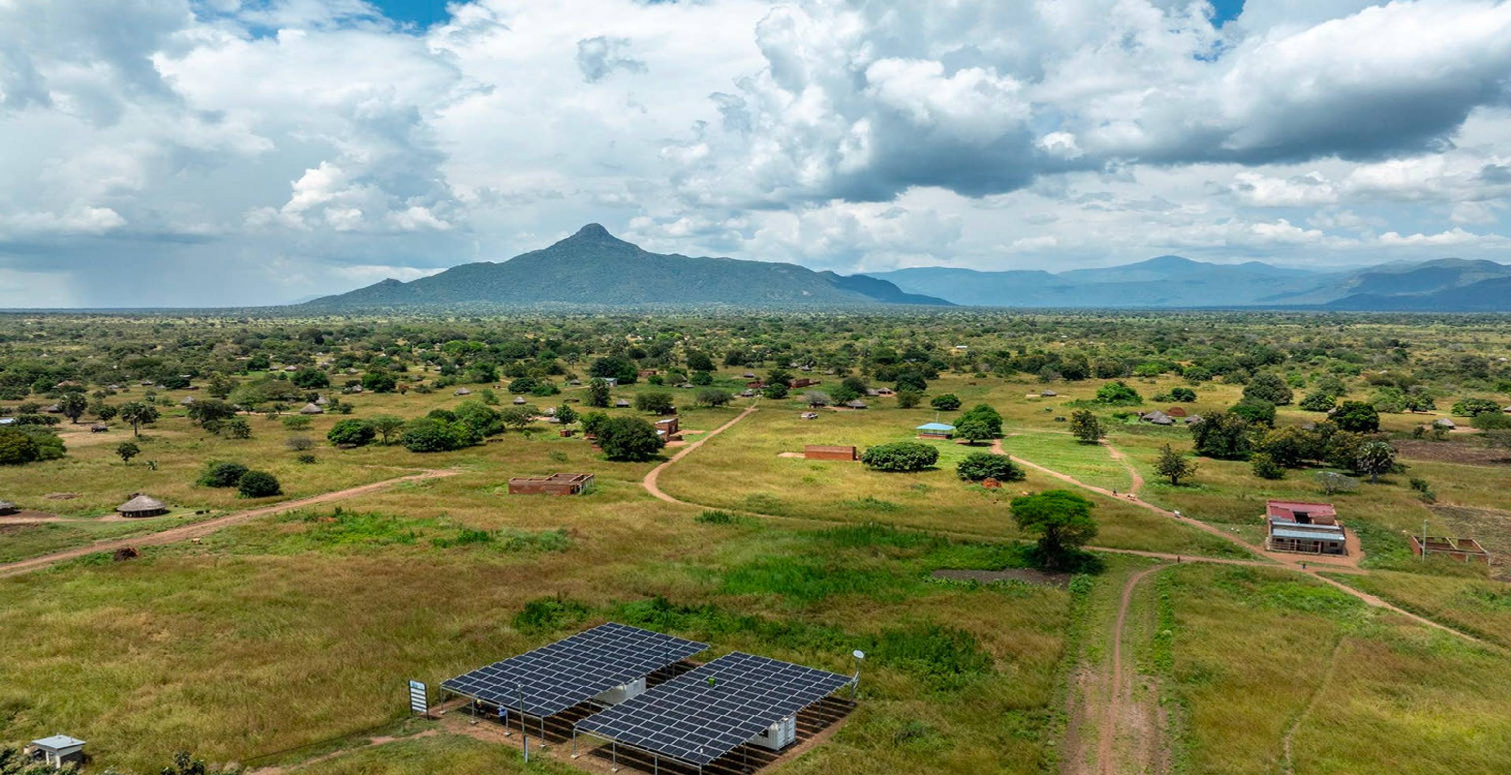 large open field with mountains in the distance. Large solar panels in the foreground