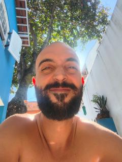 Eu, Icaro, sorrindo, de baixo para cima, sob uma árvore contra o céu.