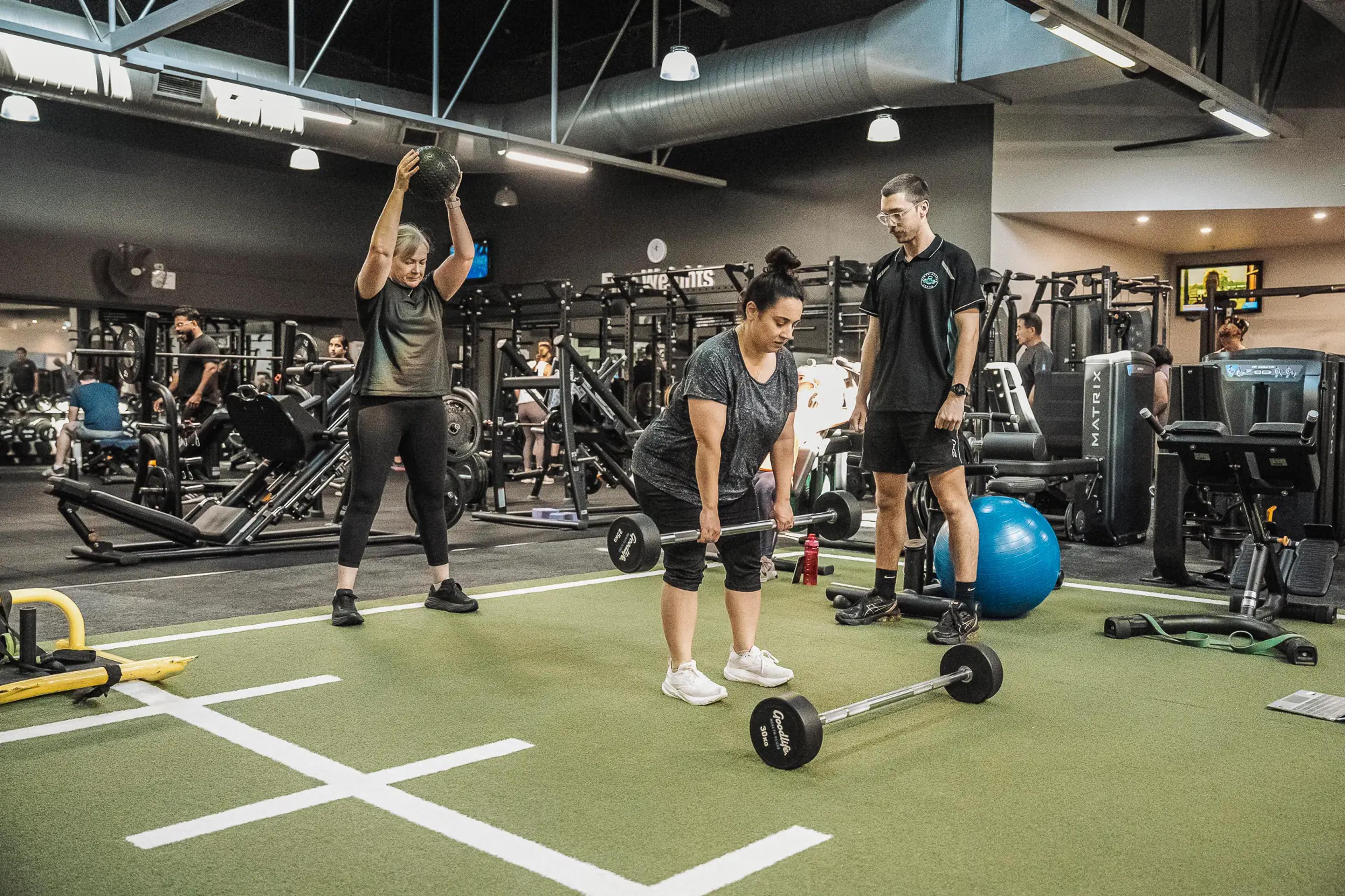 Exercise trainer guiding group strength training session, clients engaged and determined.