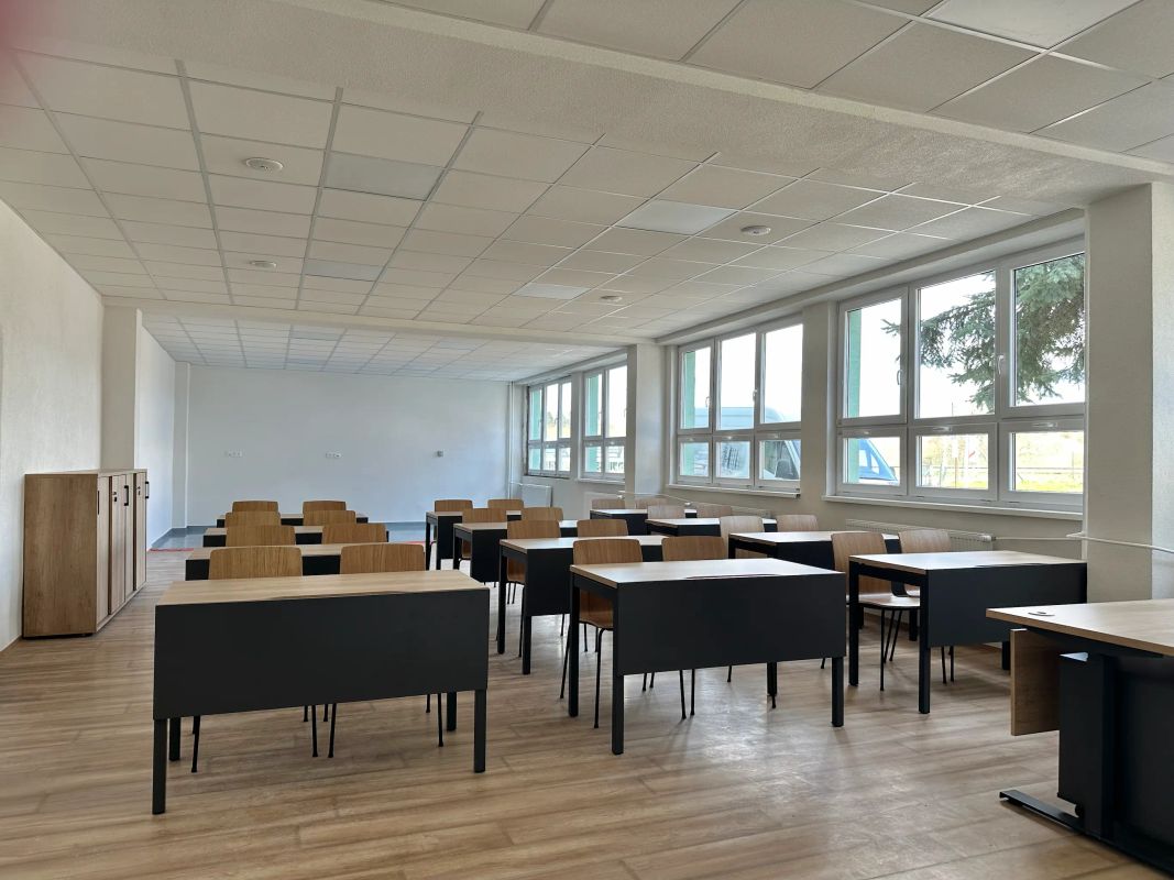 Moderná učebňa v Spišskej Novej Vsi s radmi lavíc, veľkými oknami a drevenou podlahou