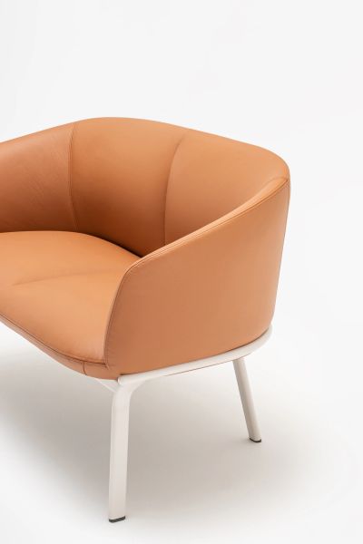 Detail oranžovej lounge pohovky Grace s oblým čalúnením a bielymi kovovými nohami