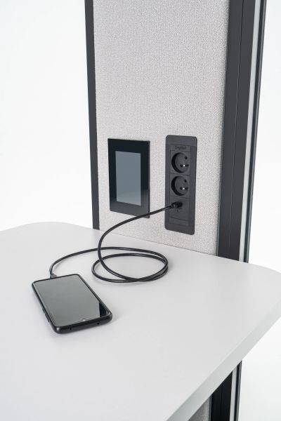 USB zásuvka a elektrické zásuvky v akustickej kabíne Coda s nabíjaným smartfónom na stole