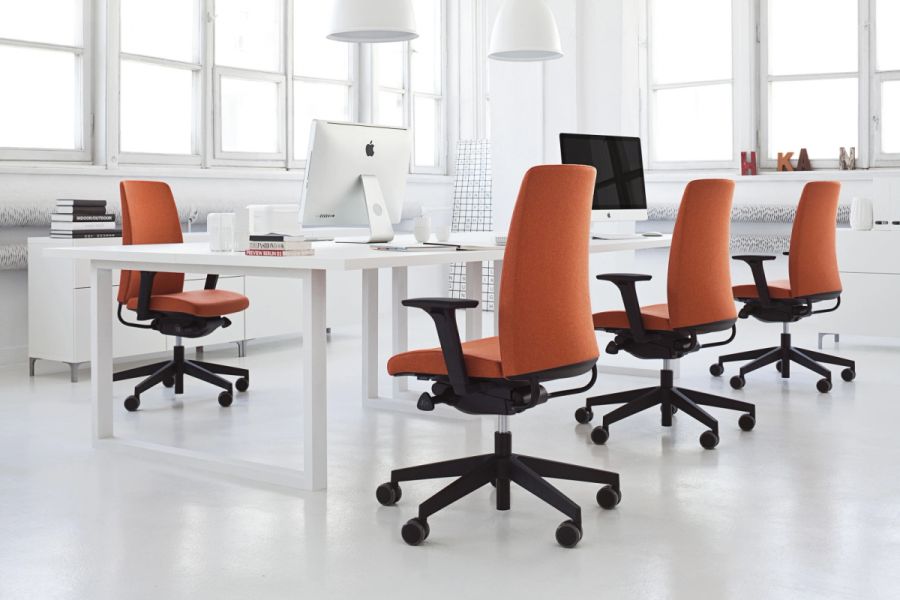 Moderná biela kancelária so štyrmi oranžovými ergonomickými stoličkami Motto pri pracovných stoloch