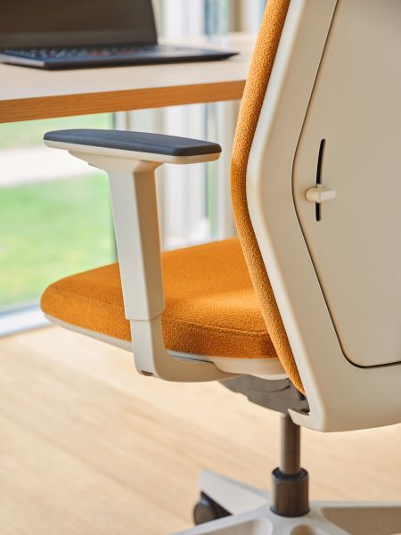 Detail ergonomickej kancelárskej stoličky Evo s oranžovým čalúnením pri pracovnom stole