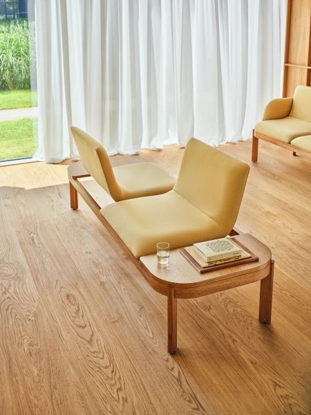 Modulárna lavica Ramp v čakárni s drevenou konštrukciou, žltými sedákmi a odkladacou plochou s knihami
