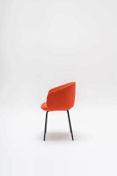 Elegantná oranžová stolička Grace s mäkkým čalúnením a čiernymi kovovými nohami v minimalistickom štúdiu