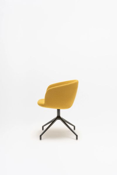 Žltá elegantná otočná stolička Grace s čiernou kovovou podnožou na štyroch nohách v minimalistickom štúdiu