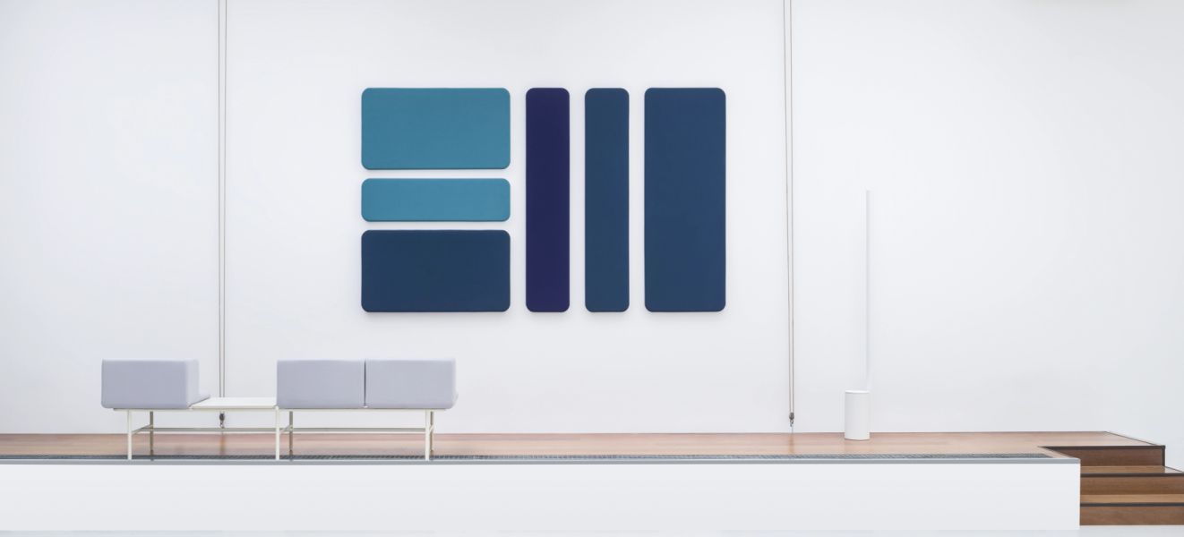 Moderné modré Sonic wall akustické panely na bielej stene v minimalistickej kancelárii so sivou lavicou