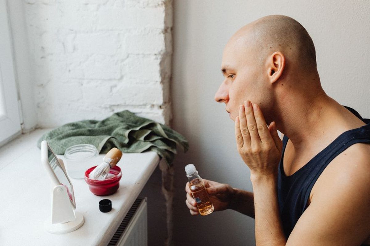 Man applying skincare fragrance hybrid product in modern bathroom grooming routine