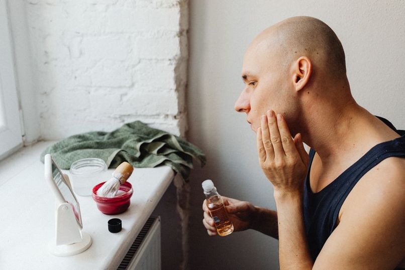 Man applying skincare fragrance hybrid product in modern bathroom grooming routine