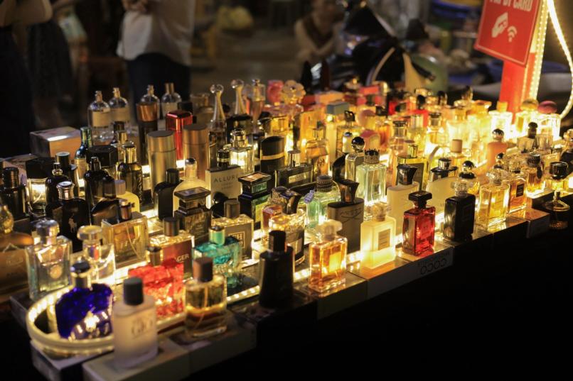 Rows of men's cologne bottles lit up on a display shelf, showcasing a wide collection of designer fragrances