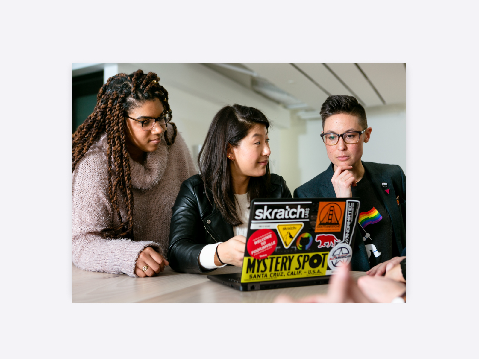 A group of young people reviewing work on a laptop.