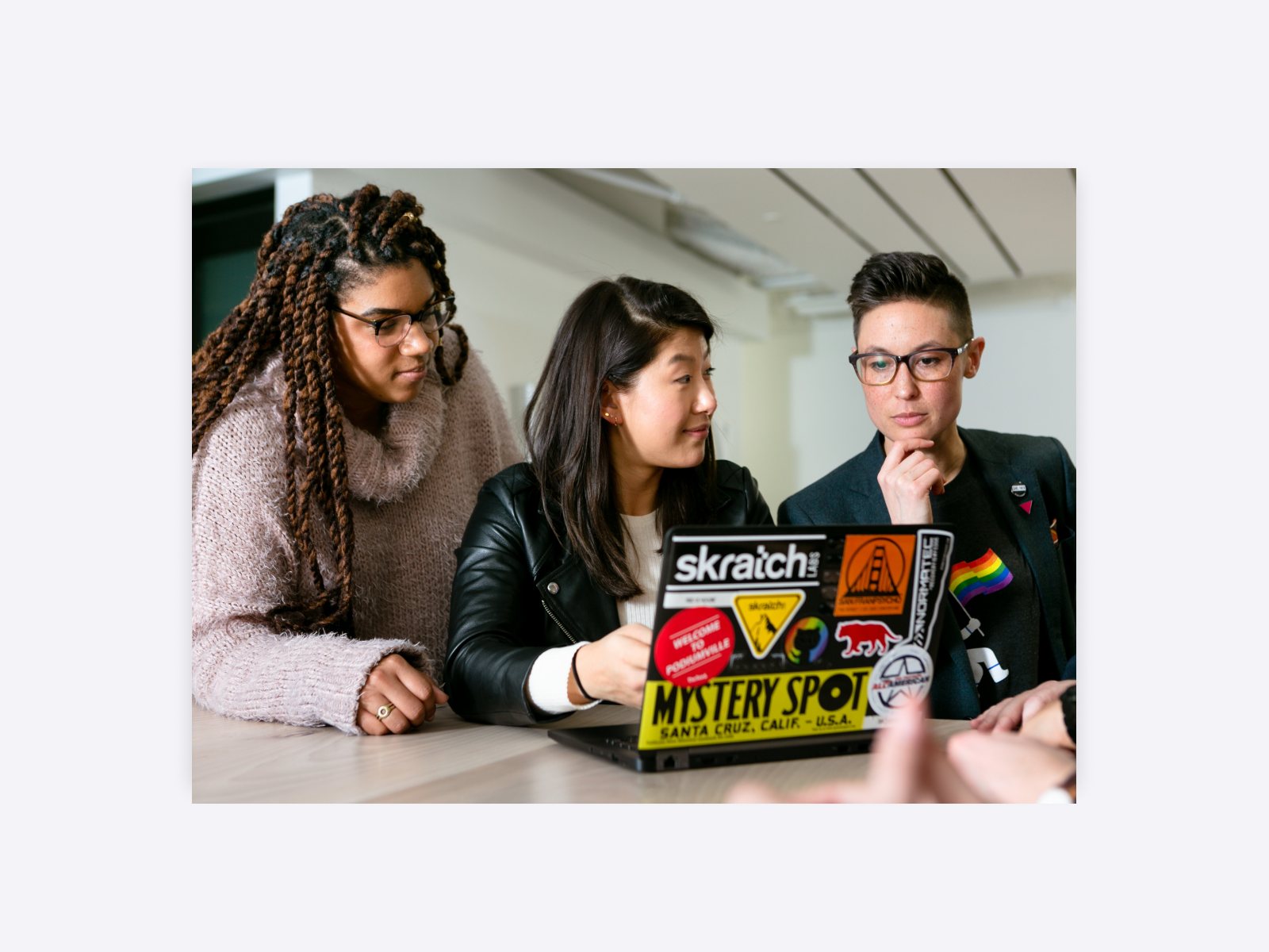 A group of young people reviewing work on a laptop. 