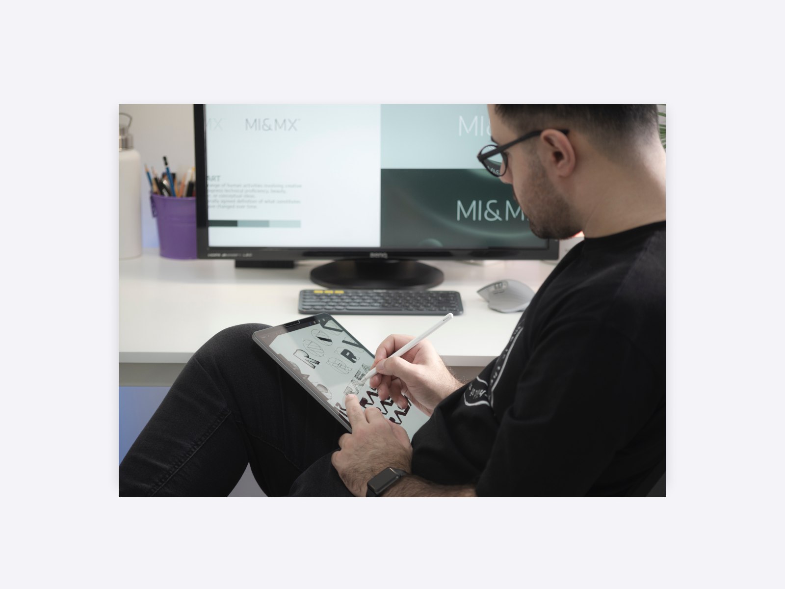 A person practicing calligraphy on a tablet, sitting in front of their computer.