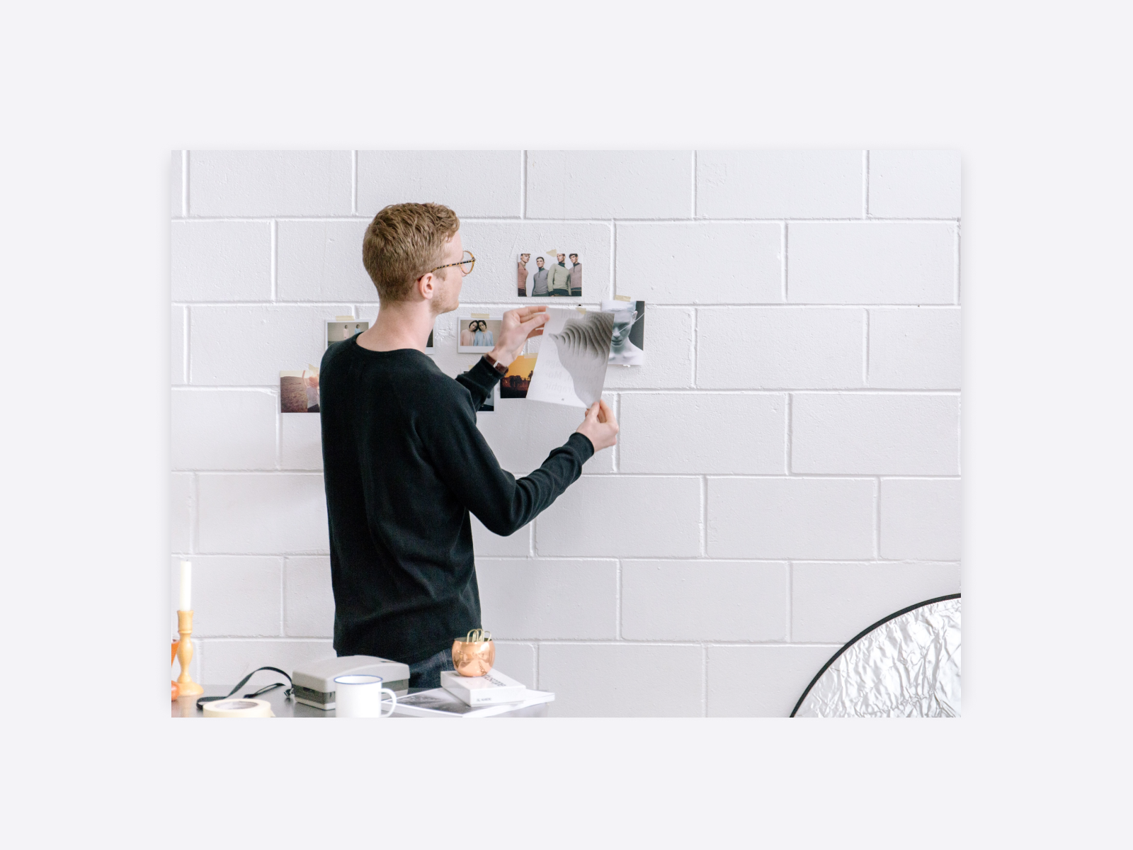 Photo of an artist placing photos on the wall, trying to select the best one.