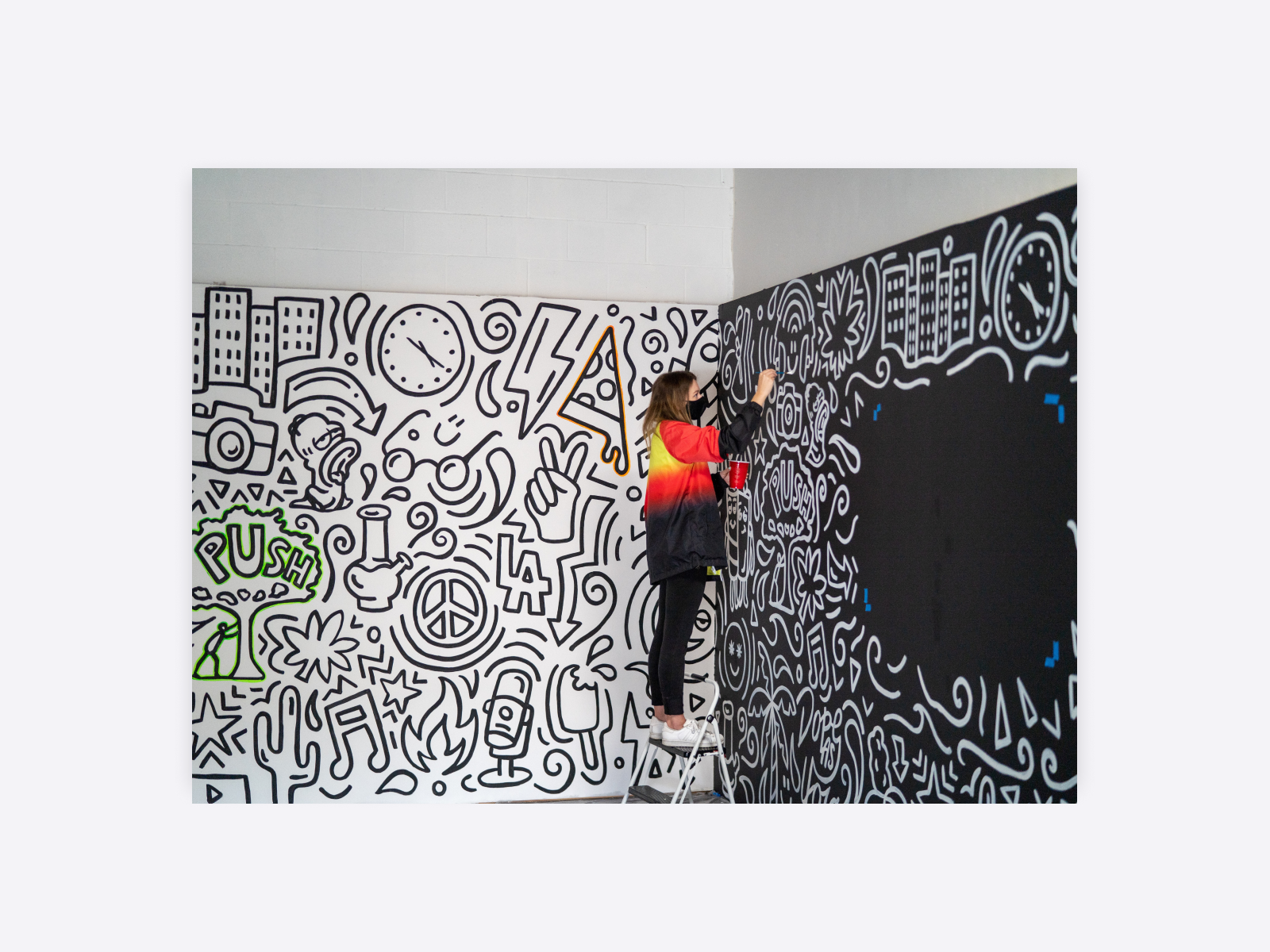 A person creating a black and white doodle mural.