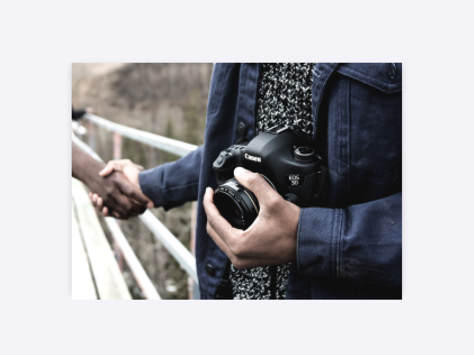 A person with a camera shaking hands with another person.
