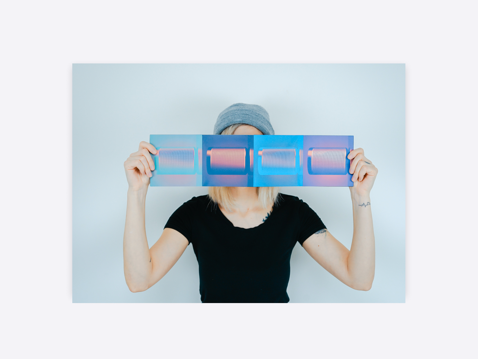 A photo of a female designer holding up photos with gradient colors in front of her face.