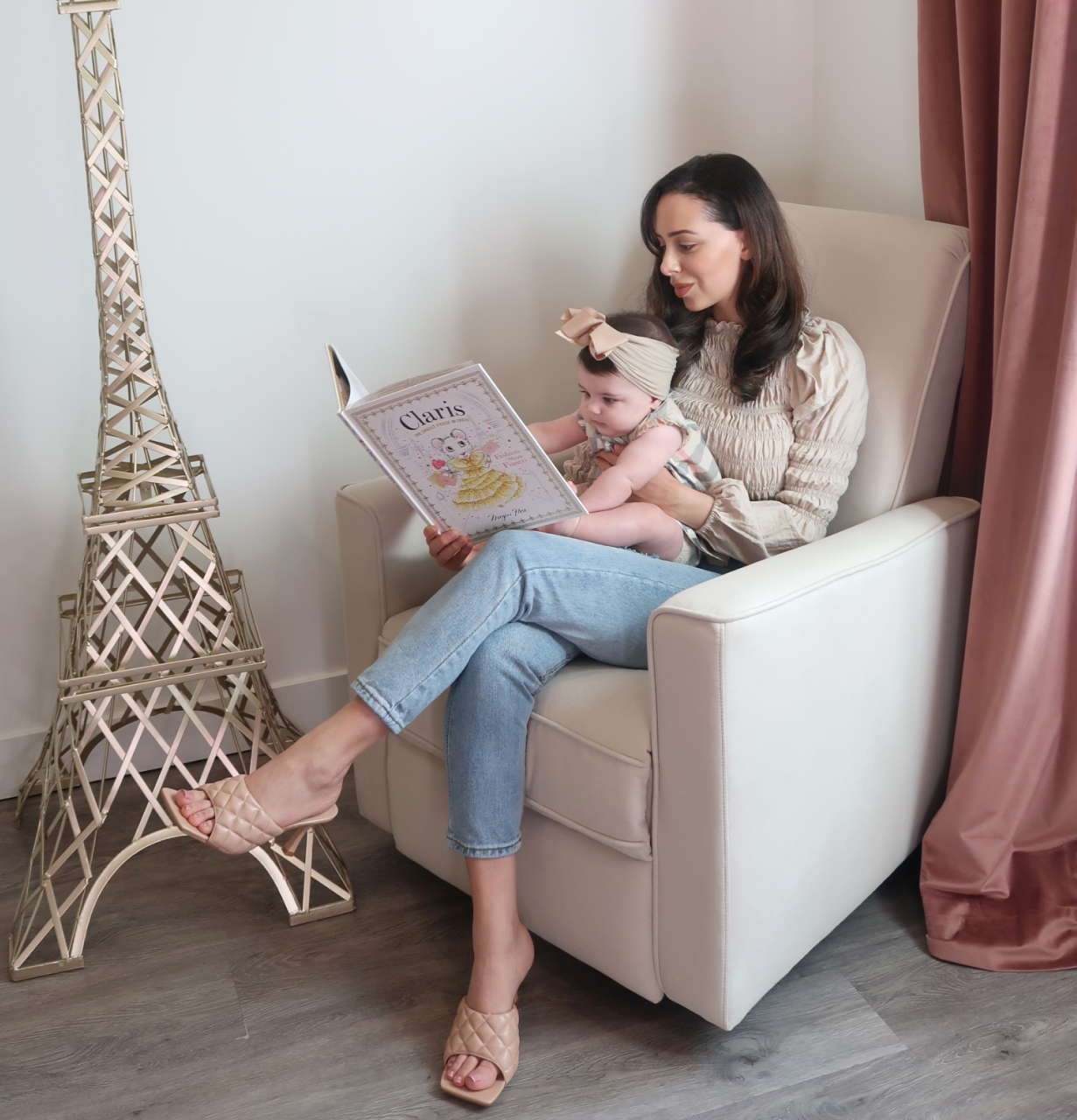 A mother sitting in Evolur Harlow Glider holding her baby while reading a children’s book