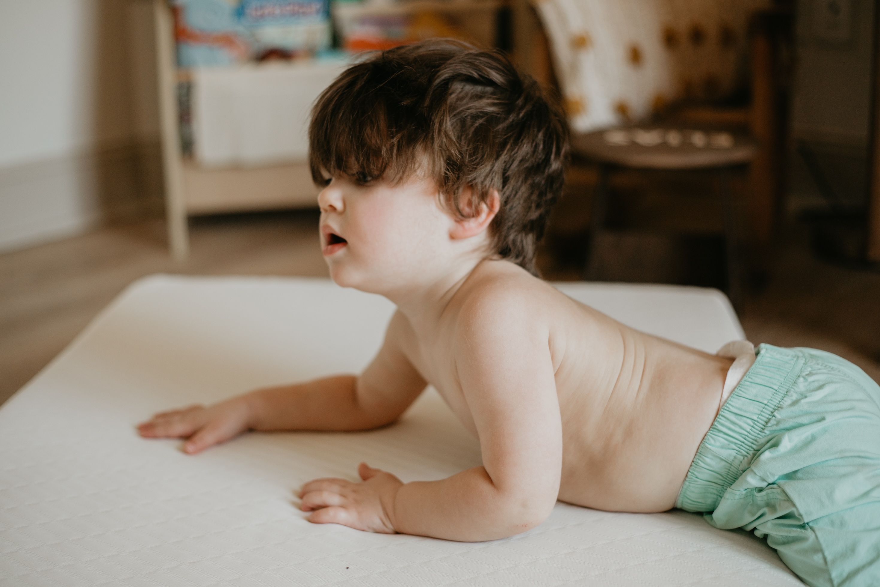 Baby crawling on a crib mattress in a cozy nursery setting
