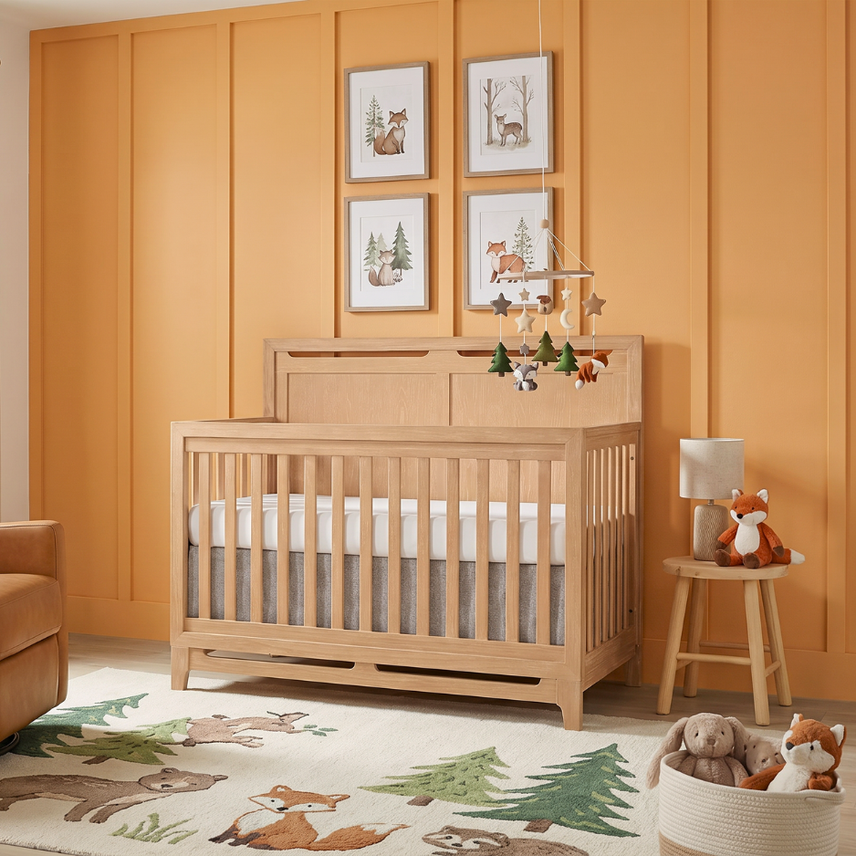 Modern wood crib in a warm nursery with orange paneled walls, woodland decor, and playful animal accents