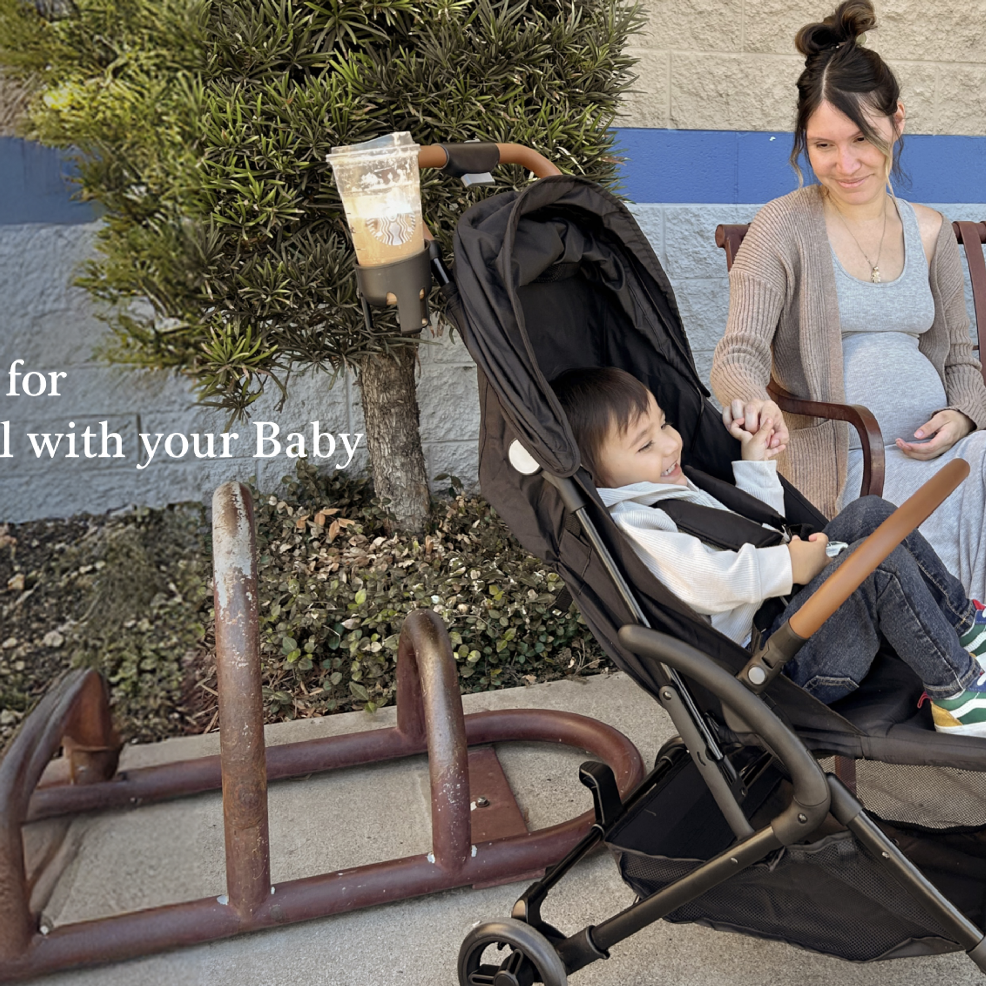 Mother sitting on a bench smiling at her young child in a Dream On Me RioGlide stroller during holiday travel.
