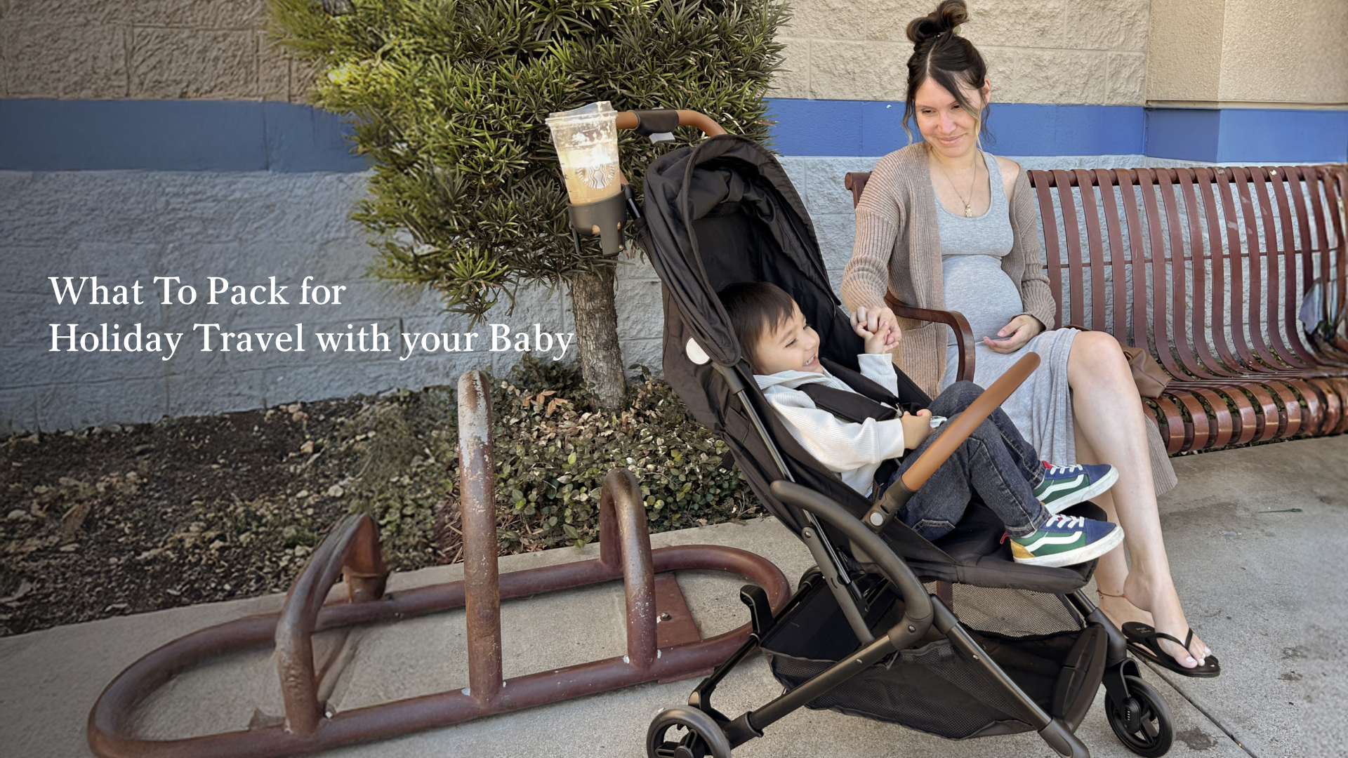 Mother sitting on a bench smiling at her young child in a Dream On Me RioGlide stroller during holiday travel.